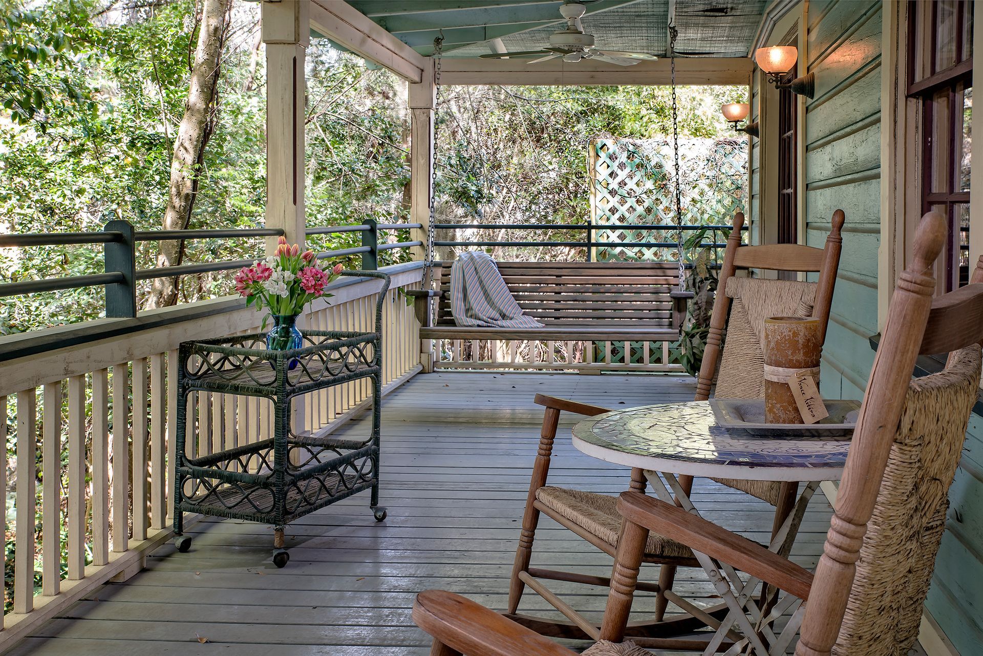 a porch with rocking chairs a table and a swing