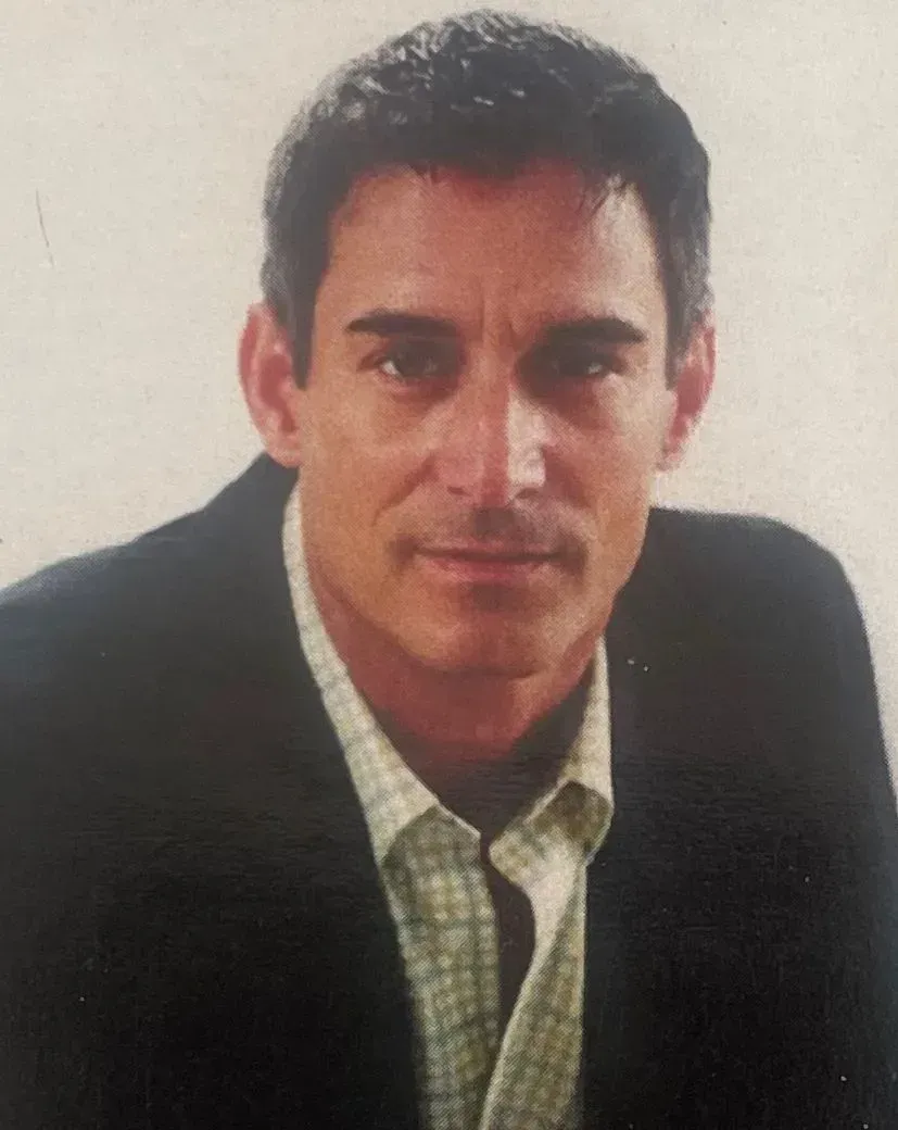 a man in a suit and plaid shirt is looking at the camera .