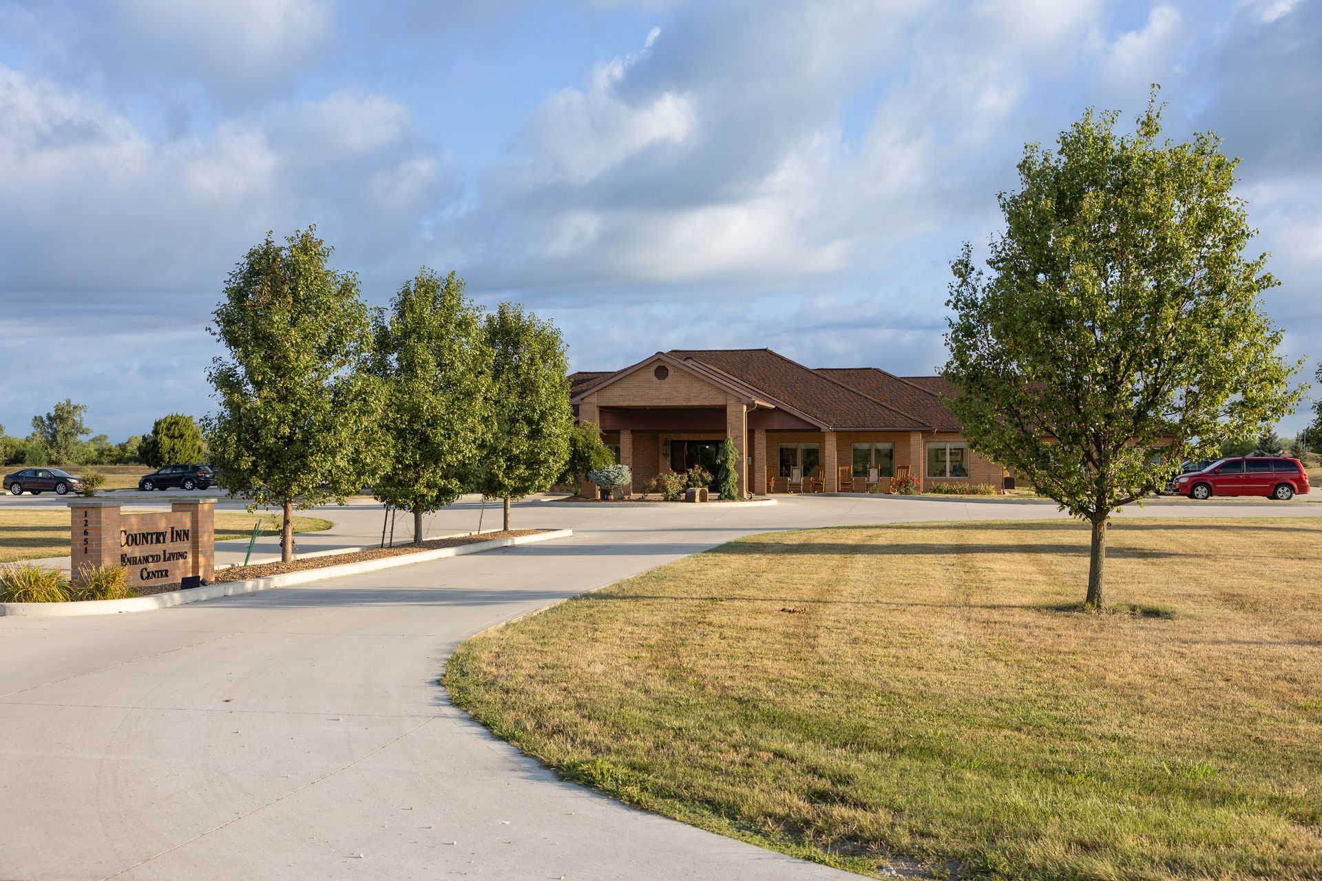 Exterior view of a single-story building with a brick facade and landscaping, a cloudy sky overhead.