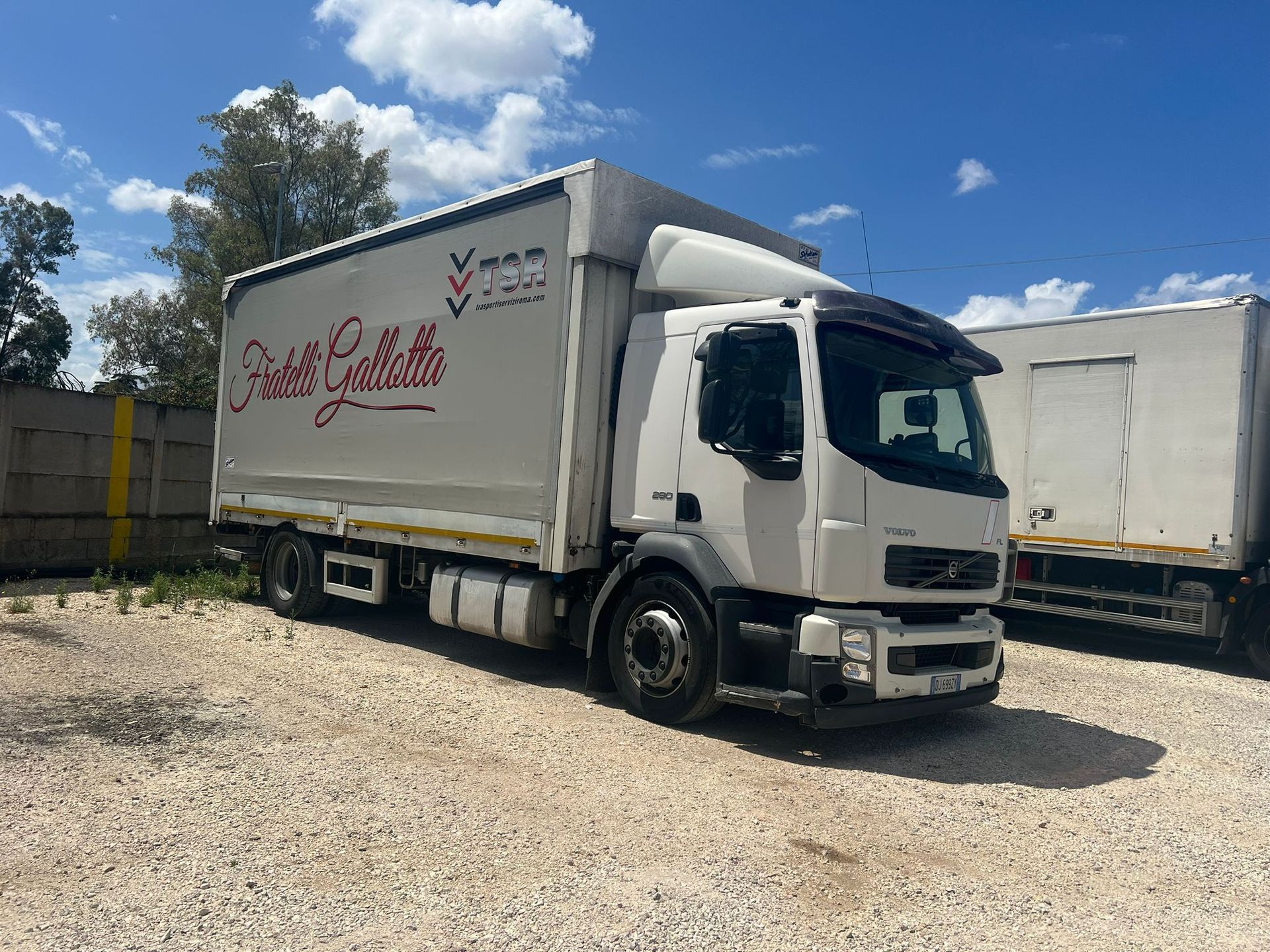 Camion Volvo bianco parcheggiato sulla ghiaia; sul lato del camion c'è il logo rosso
