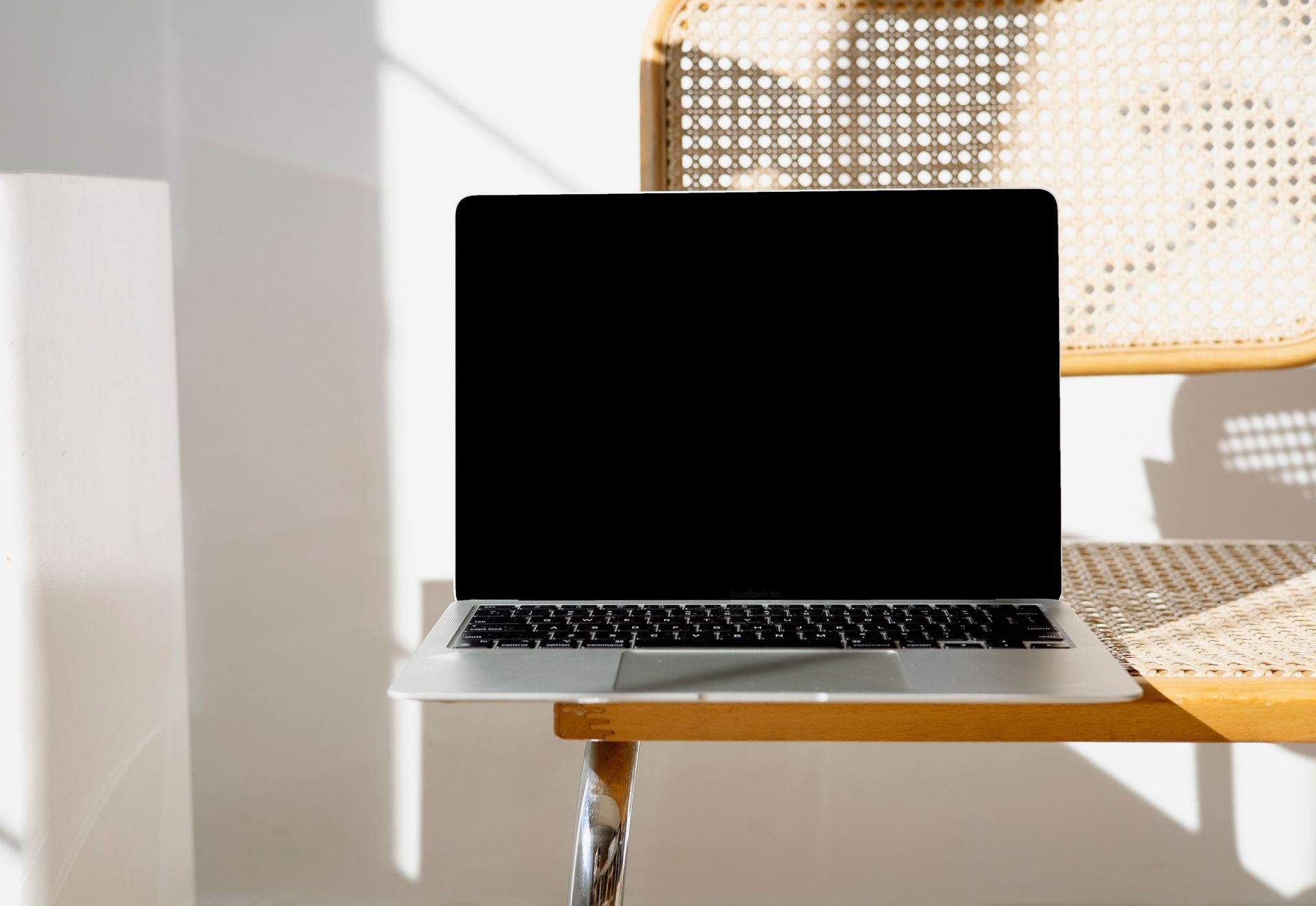 Green chair beside a wooden desk with laptop, notebook, phone, and glasses in a warm-lit room
