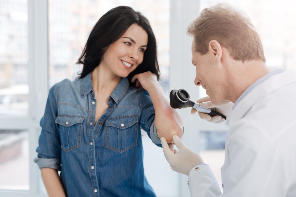 A Doctor is Examining a Woman 's Elbow With a Magnifying Glass — One Stop Medical in Mackay, QLD