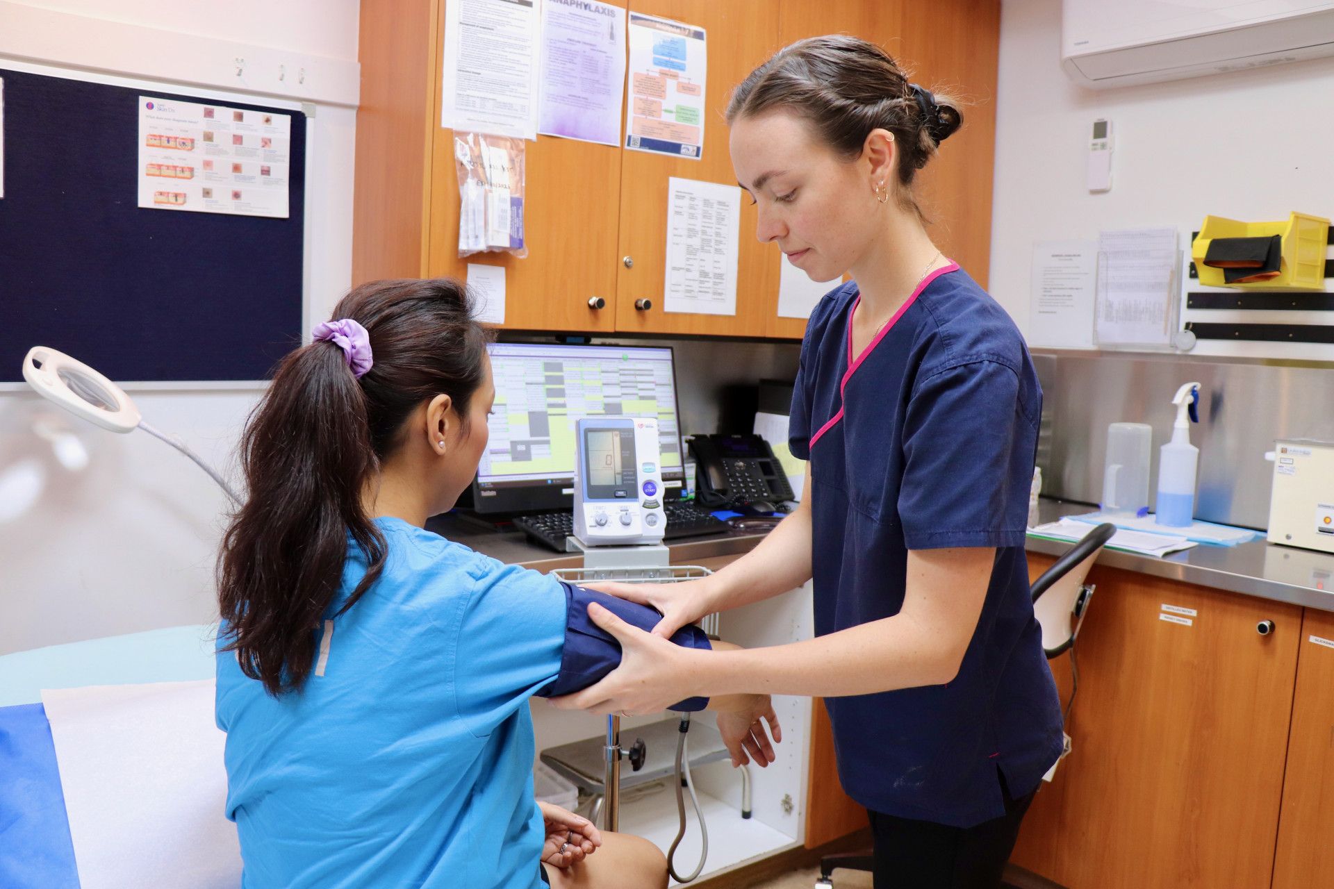 Nurse taking patient's blood pressure in a medical examination room; blue scrubs.— One Stop Medical in Mackay, QLD