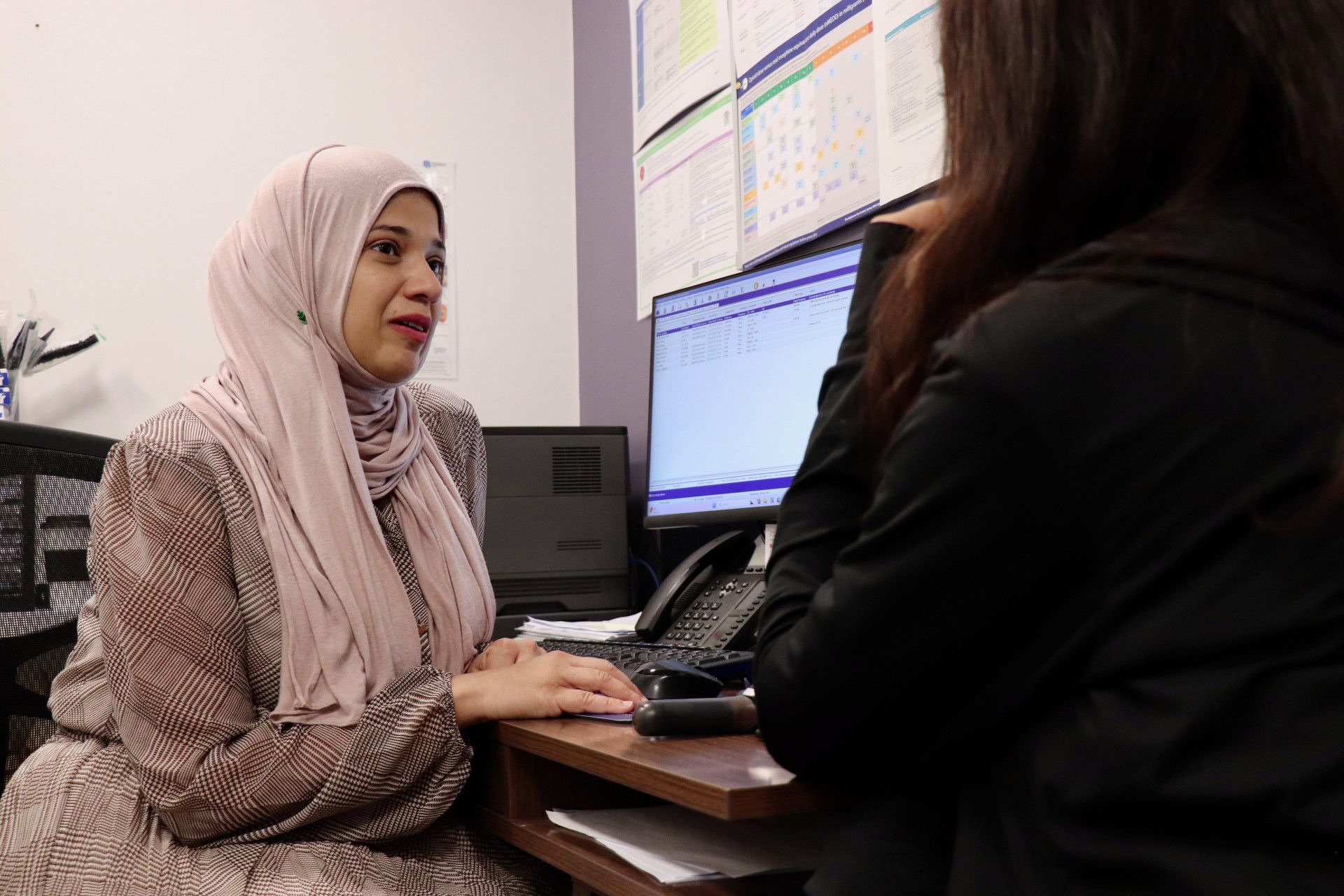 Woman in Hijab Talking to Someone at A Desk in An Office. — One Stop Medical in Mackay, QLD