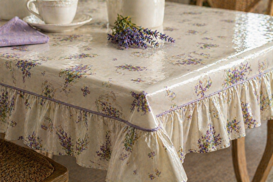 Una tovaglia floreale su un tavolo con stoviglie bianche e rametti di lavanda in una cucina luminosa.