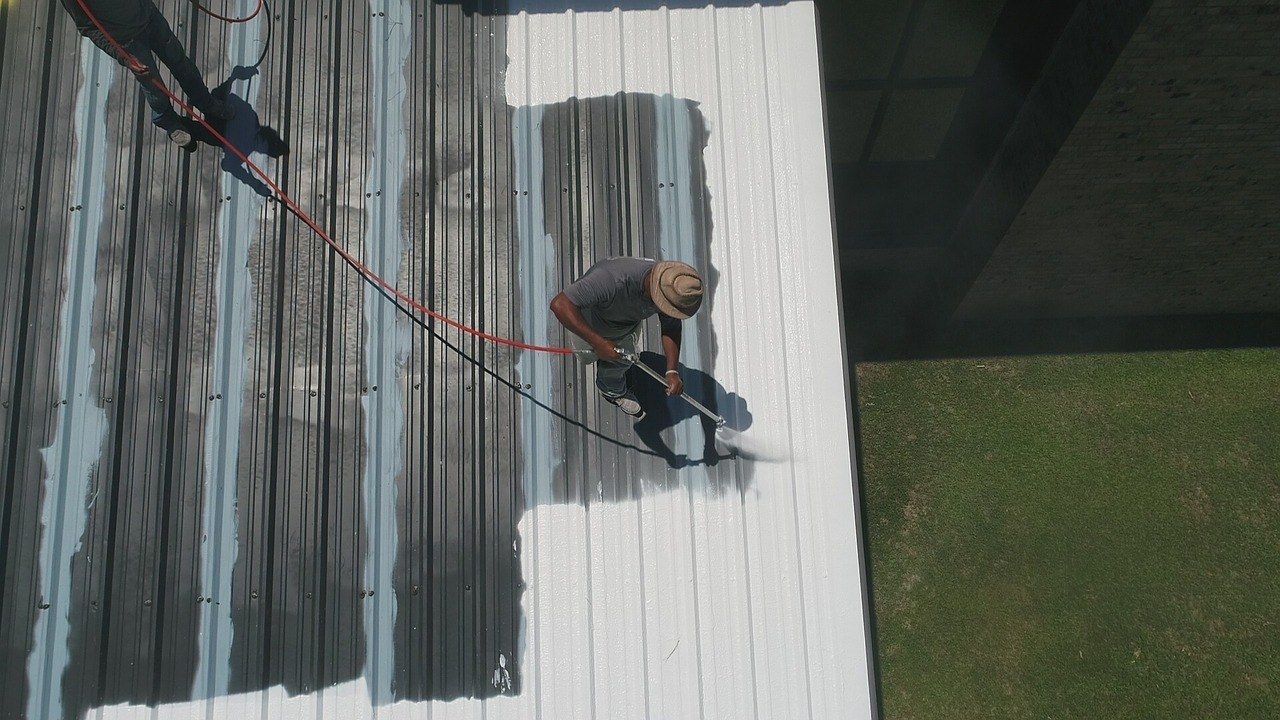 Overhead shot of a person painting a white surface with a spray gun. Black paint contrasts the white section.