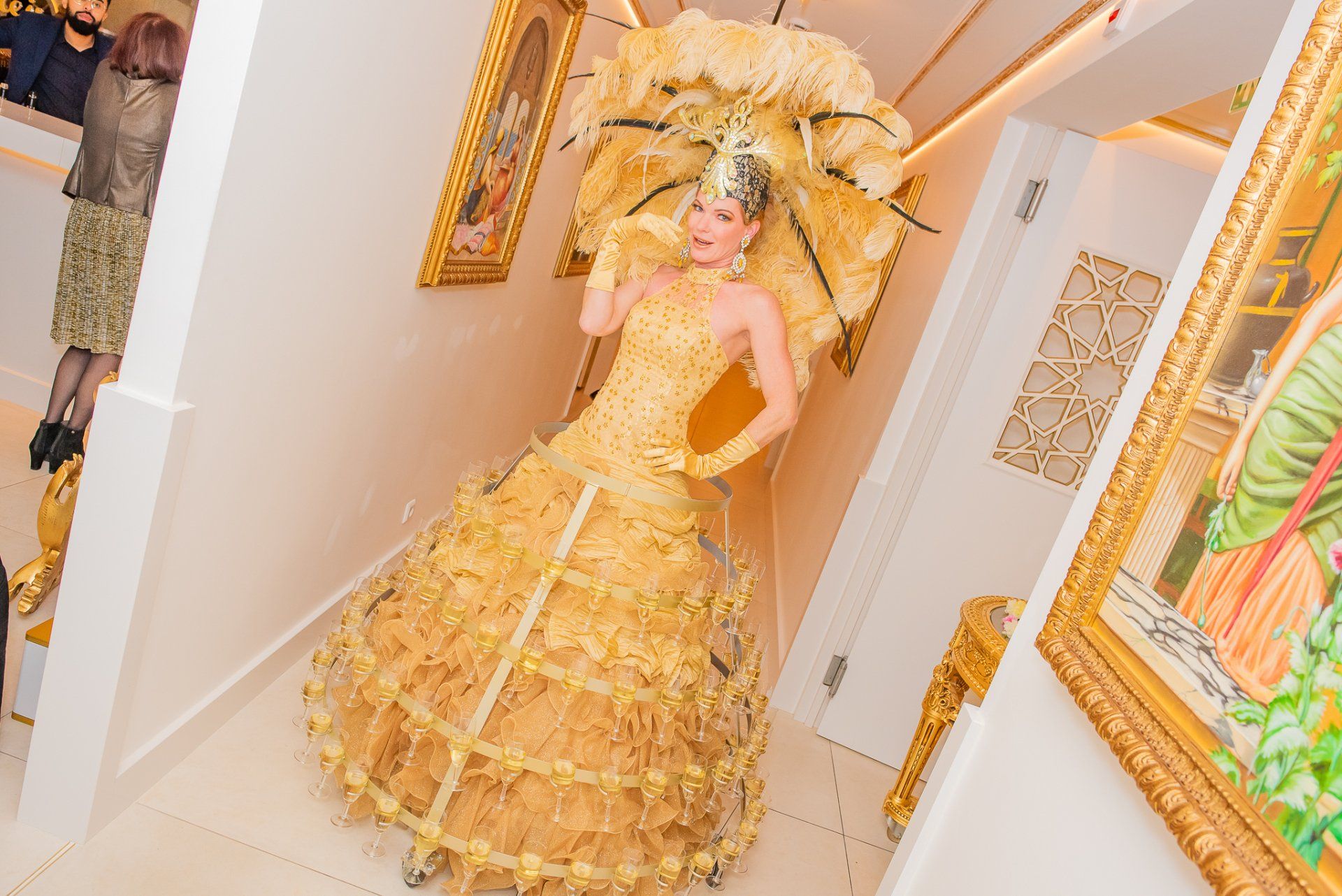Gouden mannequin in een sierlijke jurk en met een parasol, in een lichte, met kunst gevulde kamer.