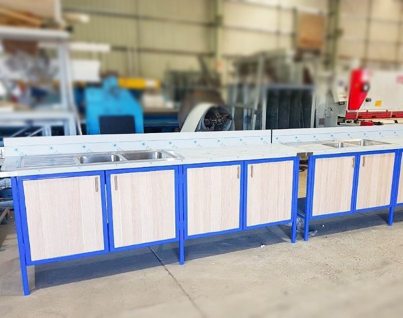 A row of blue and wooden cabinets with sinks in a warehouse.