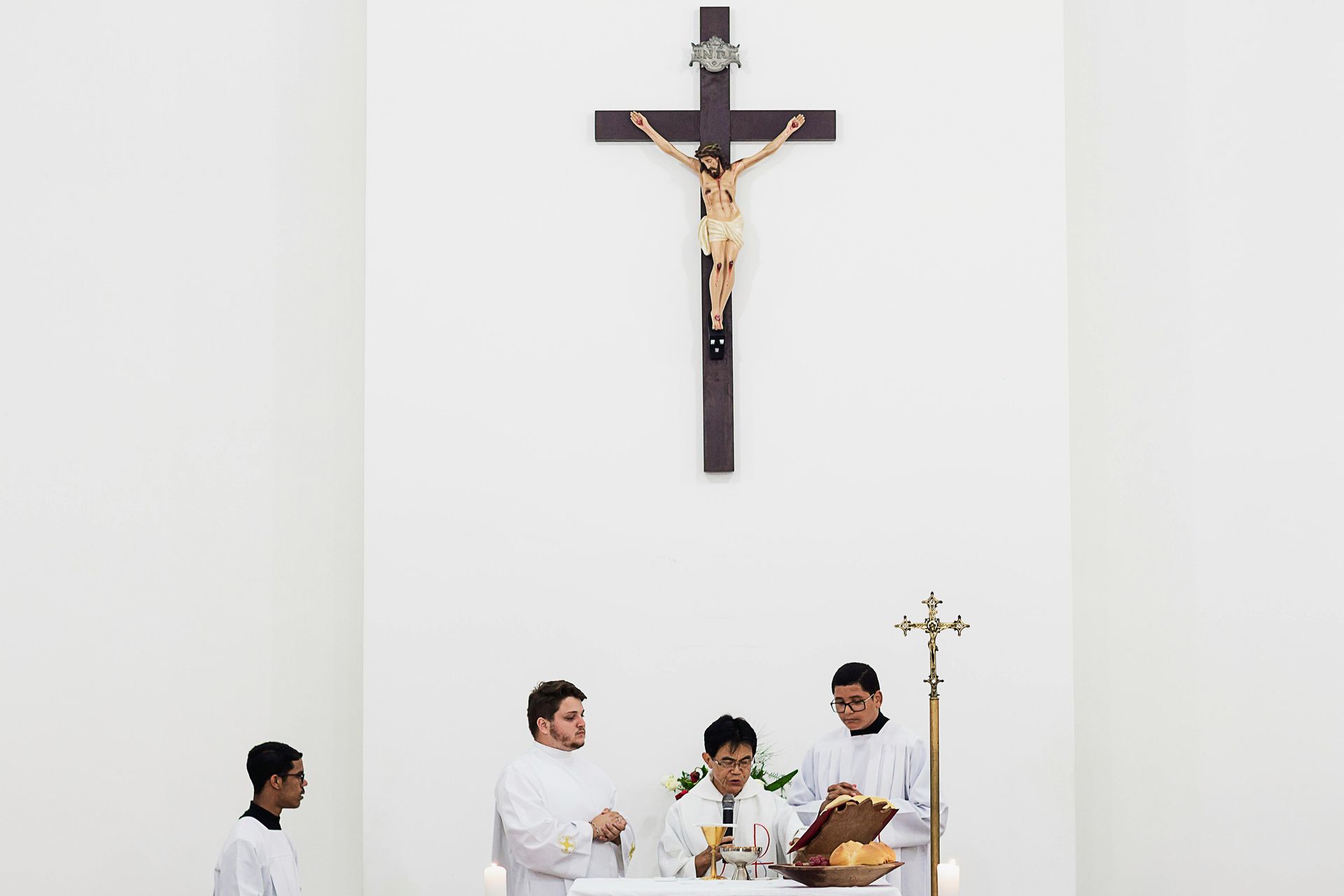 A religious service with people near a table, under a crucifix.