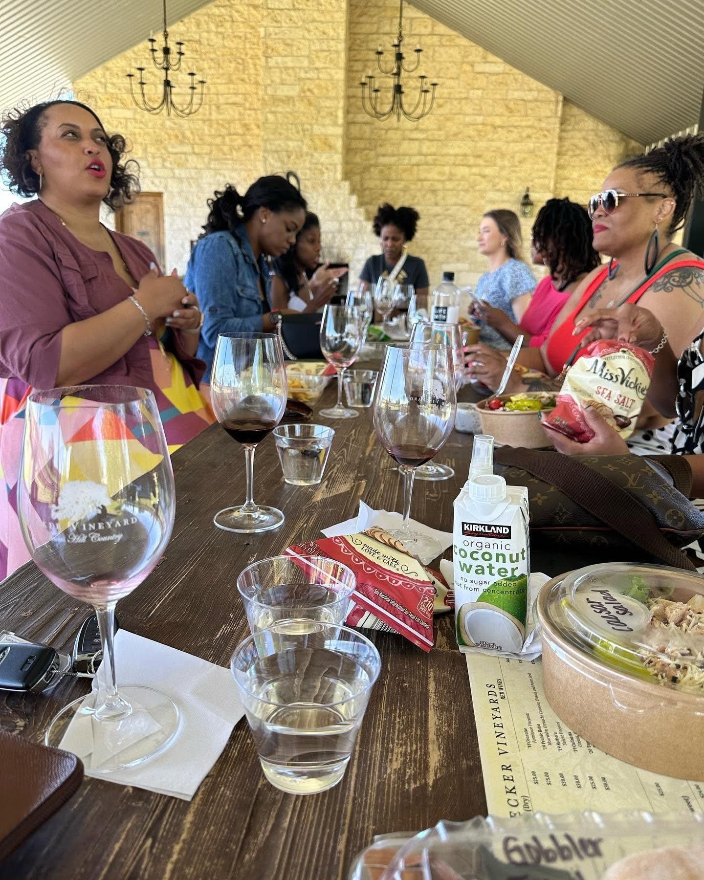 People seated at a long table in a rustic restaurant, talking over wine and water glasses