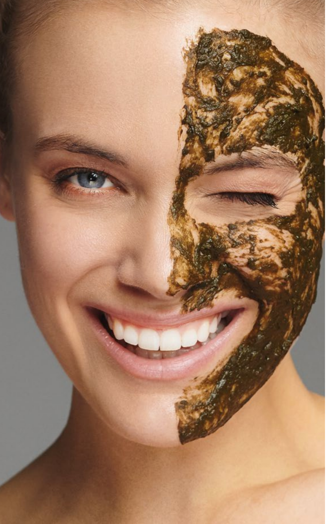 A woman is getting a blue mask on her face.