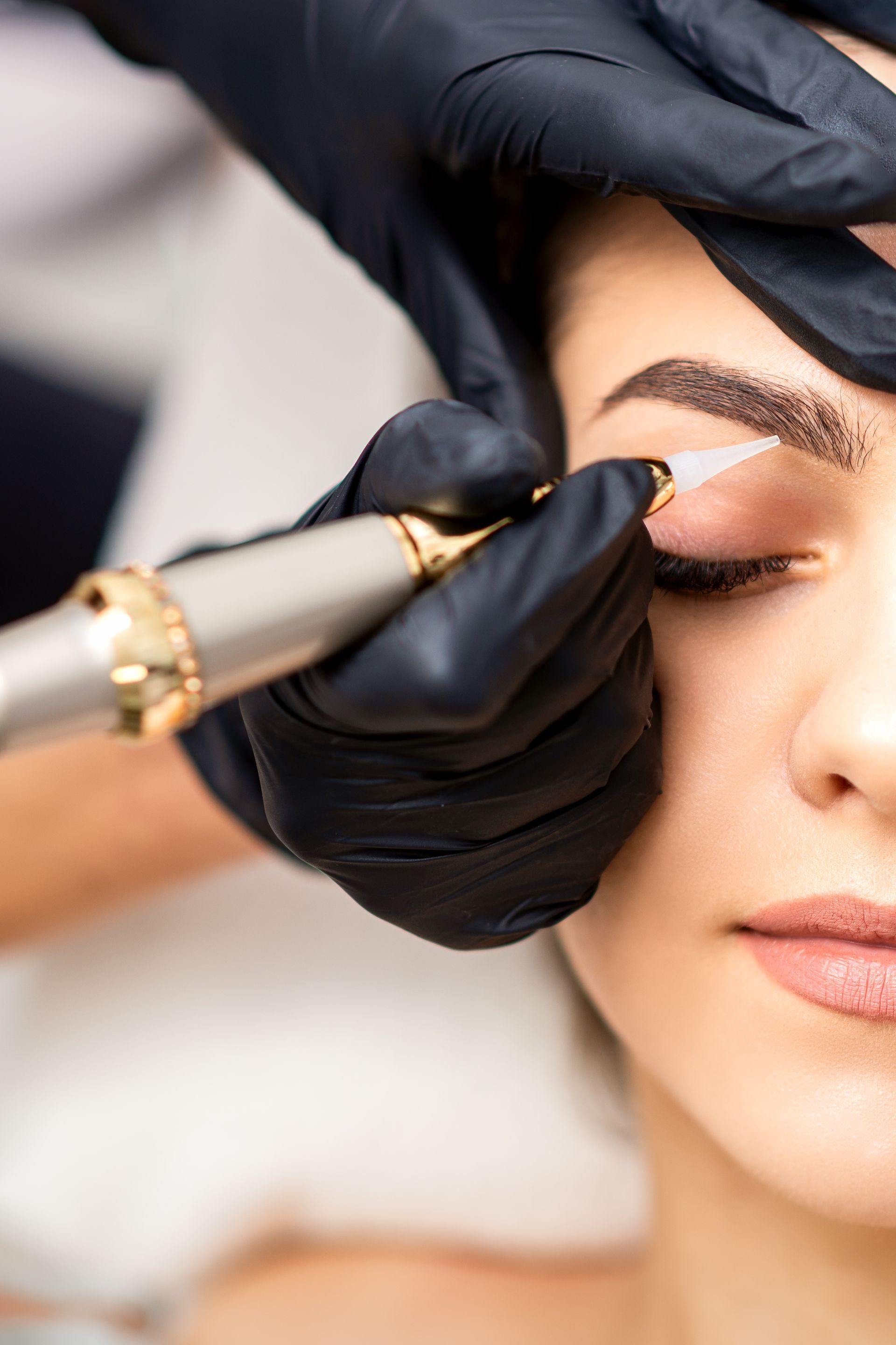 a woman is getting her eyebrows tattooed with a pen .