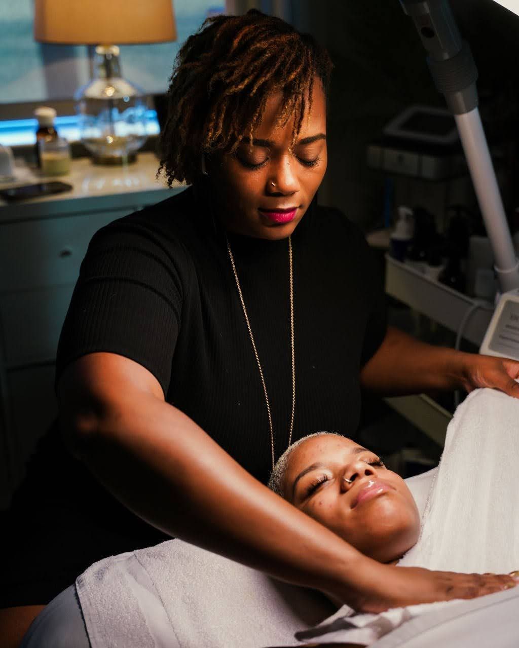 A woman is examining a woman 's face under a magnifying glass in a beauty salon.