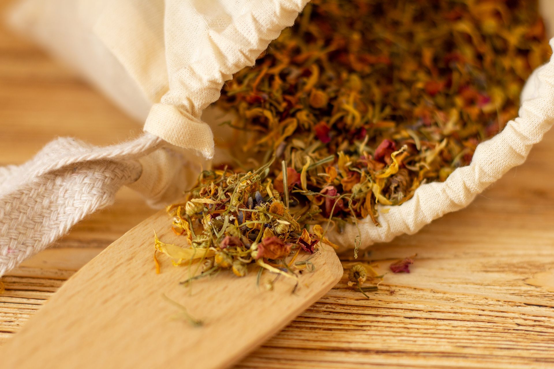 a bag of dried herbs and a wooden spoon on a wooden table .