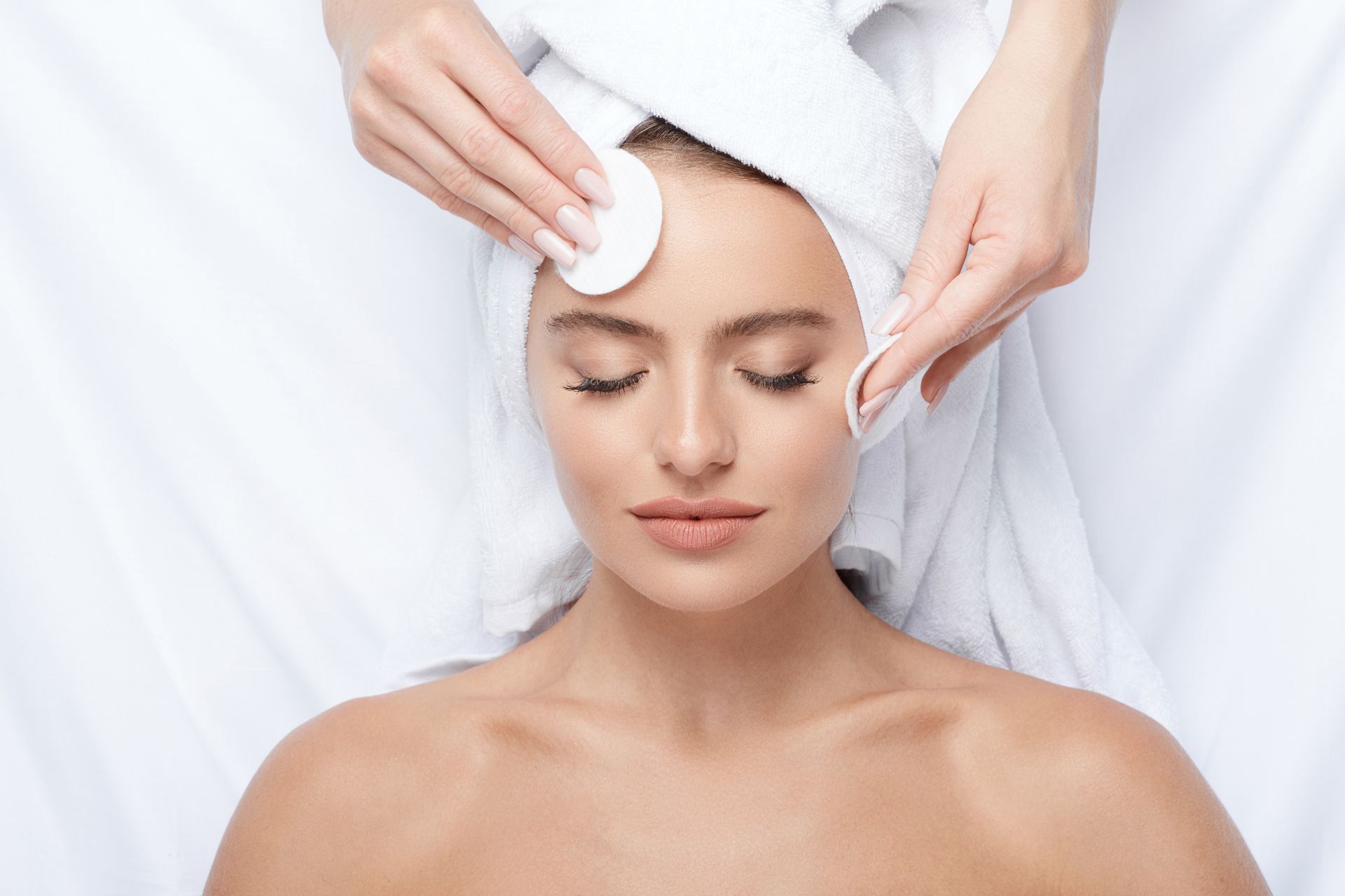 a woman with a towel wrapped around her head is getting a facial treatment .