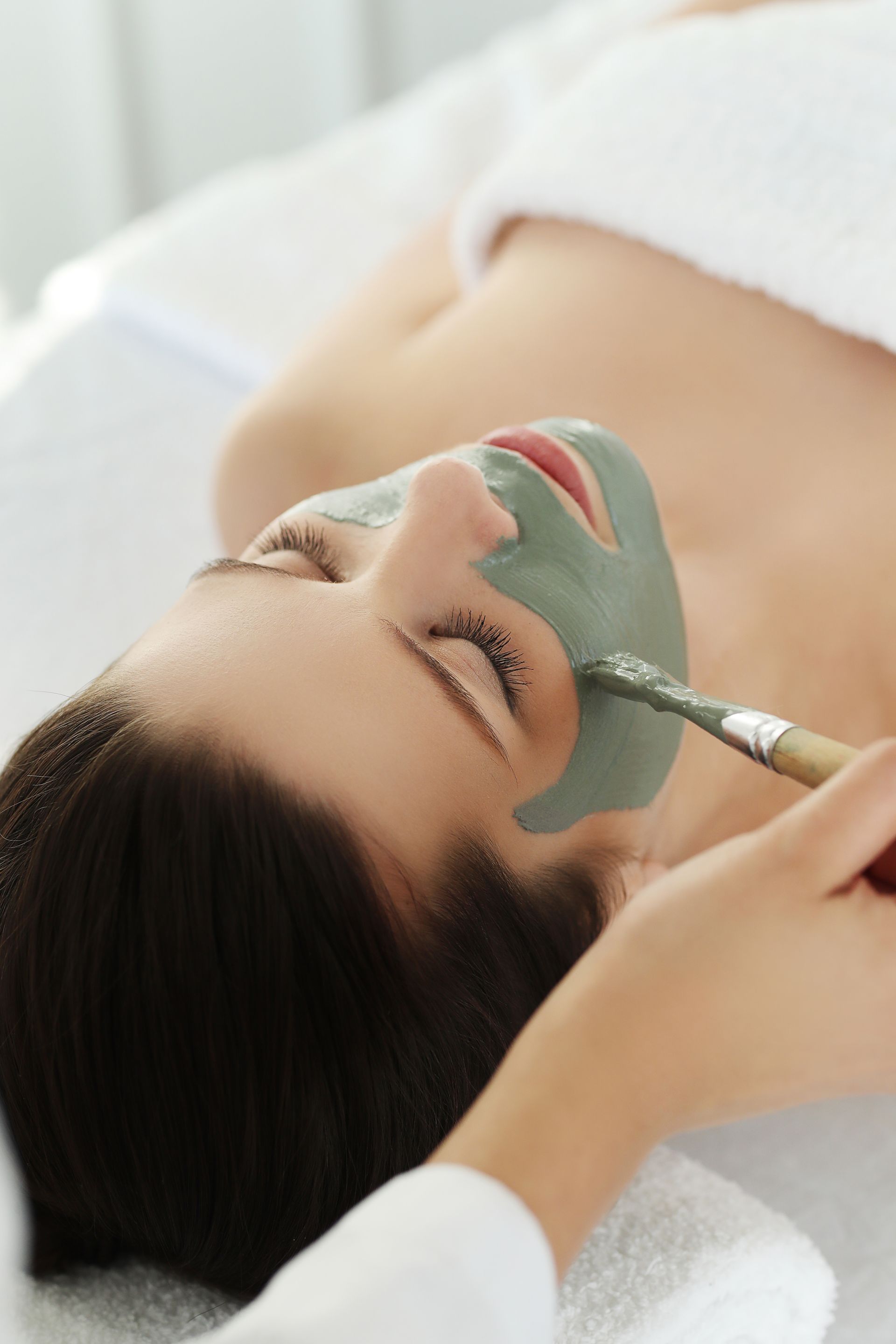 a woman is getting a facial treatment with a brush .