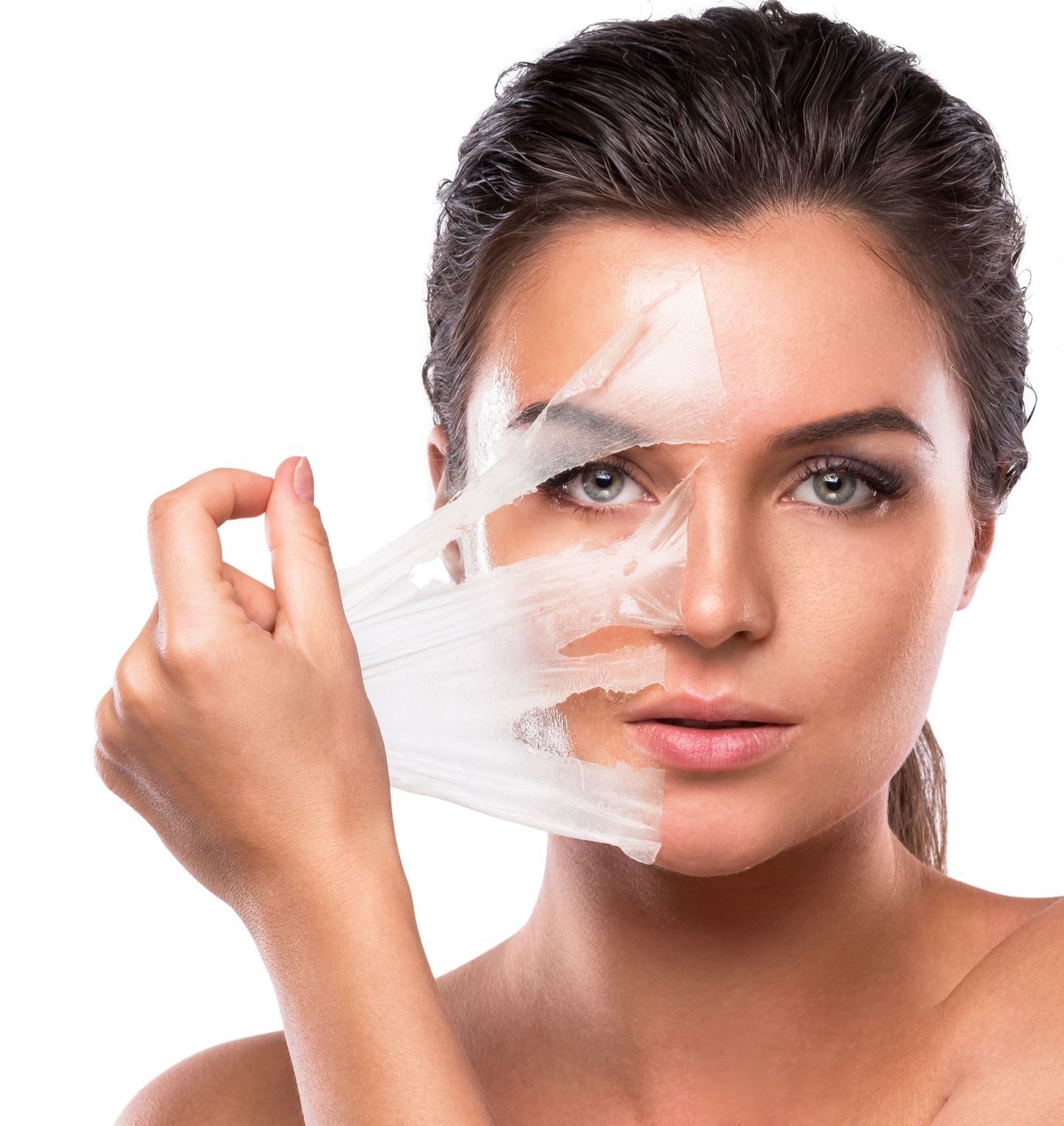 A woman is peeling off a plastic mask from her face.