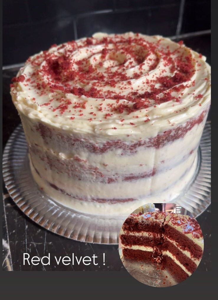 Pastel de terciopelo rojo con glaseado de queso crema sobre un plato de vidrio.