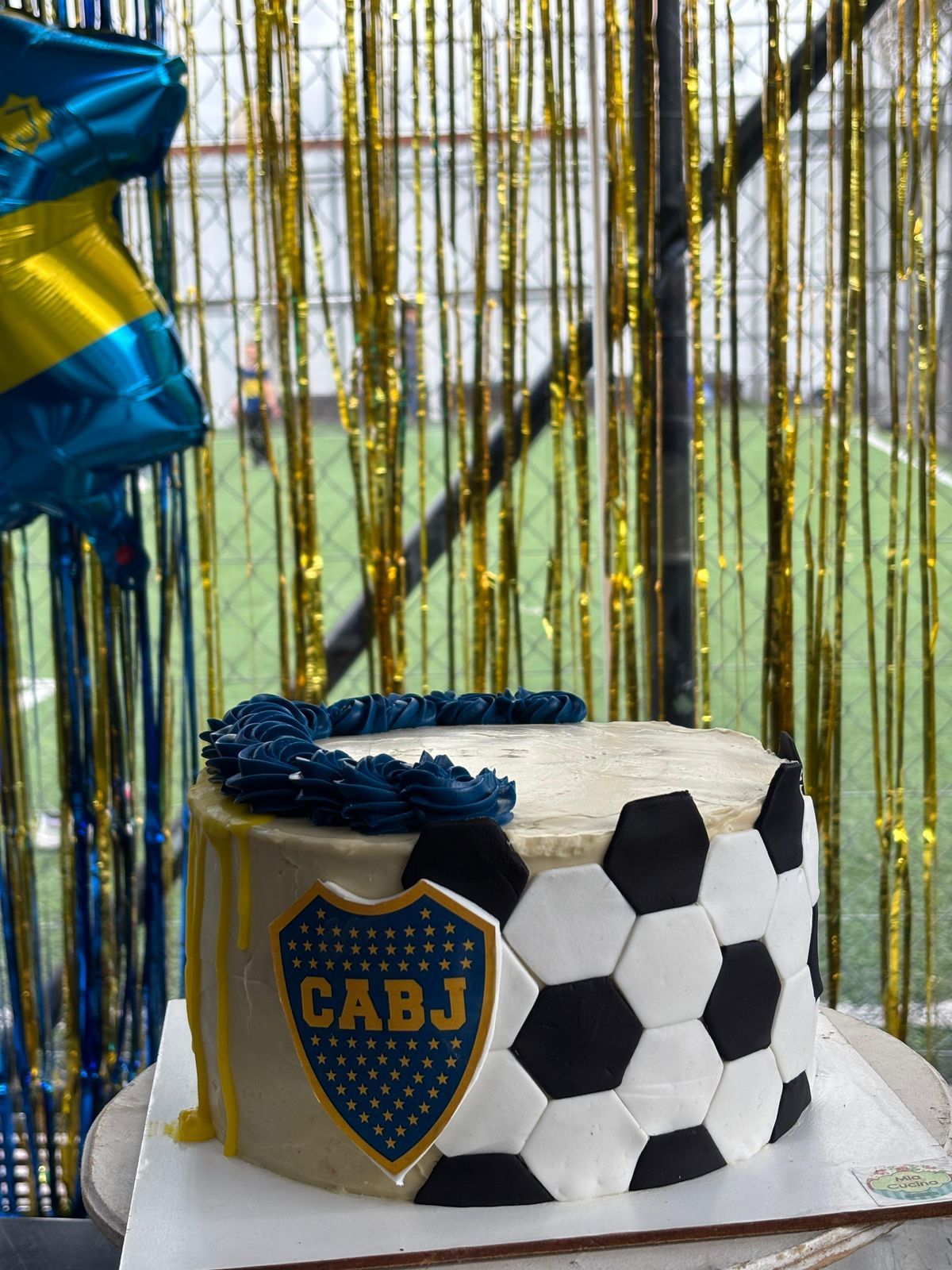 Torta decorada con dibujo de pelota de fútbol y el logo de Boca Juniors; temática azul y dorado.
