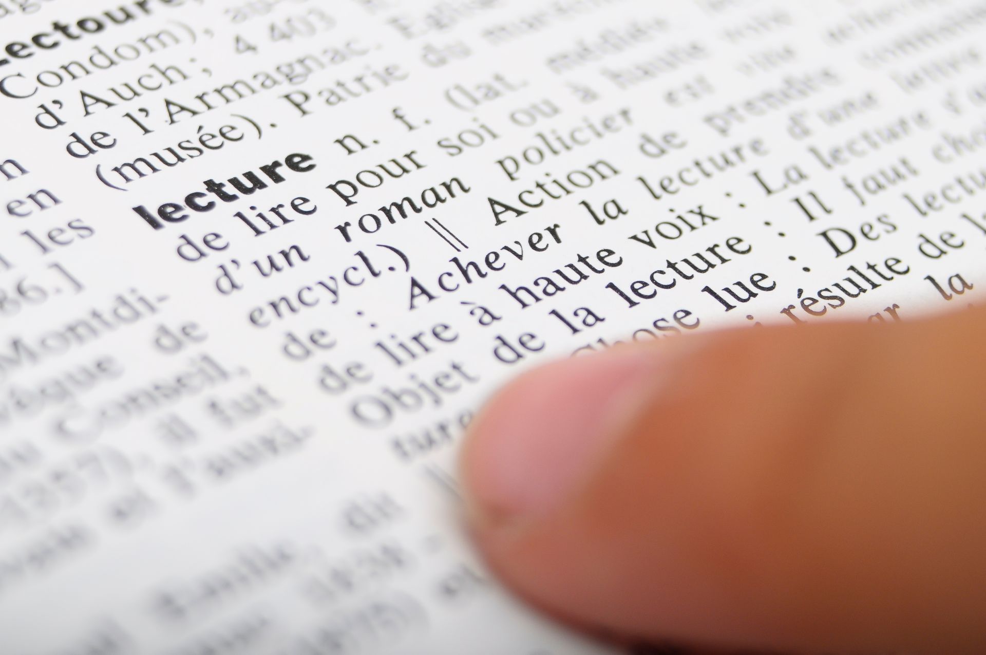 Pointage du doigt vers le mot « conférence » dans un dictionnaire. Le texte est en français.