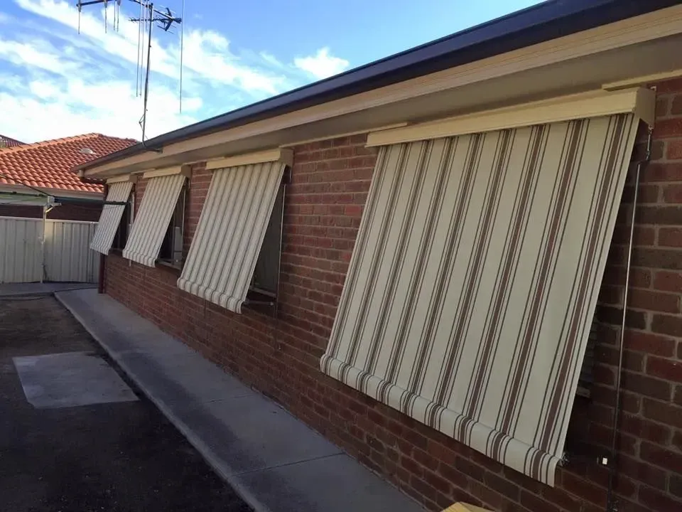 A Brick Building With Striped Awnings On The Windows — Spring Crest Blinds, Awnings & Security Doors in Shepparton, VIC