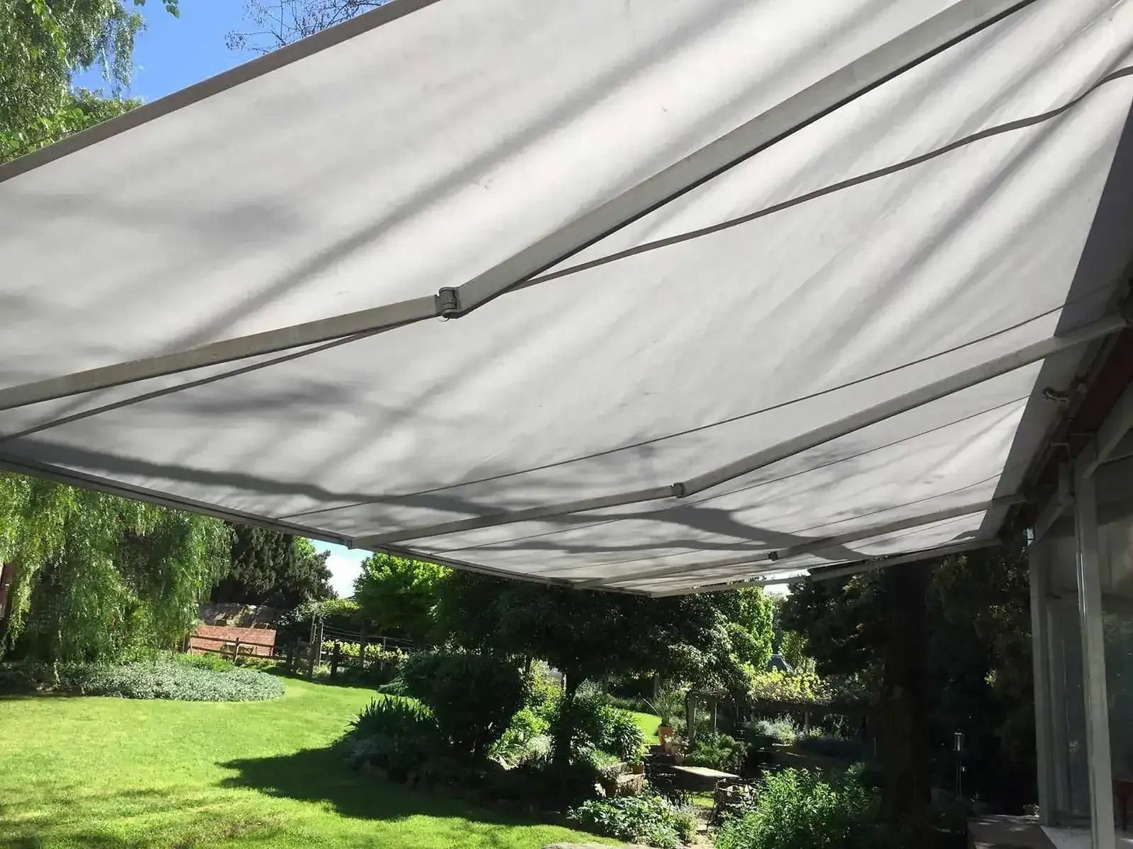 A Large White Awning Is Hanging Over A Lush Green Field — Spring Crest Blinds, Awnings & Security Doors in Melbourne, VIC