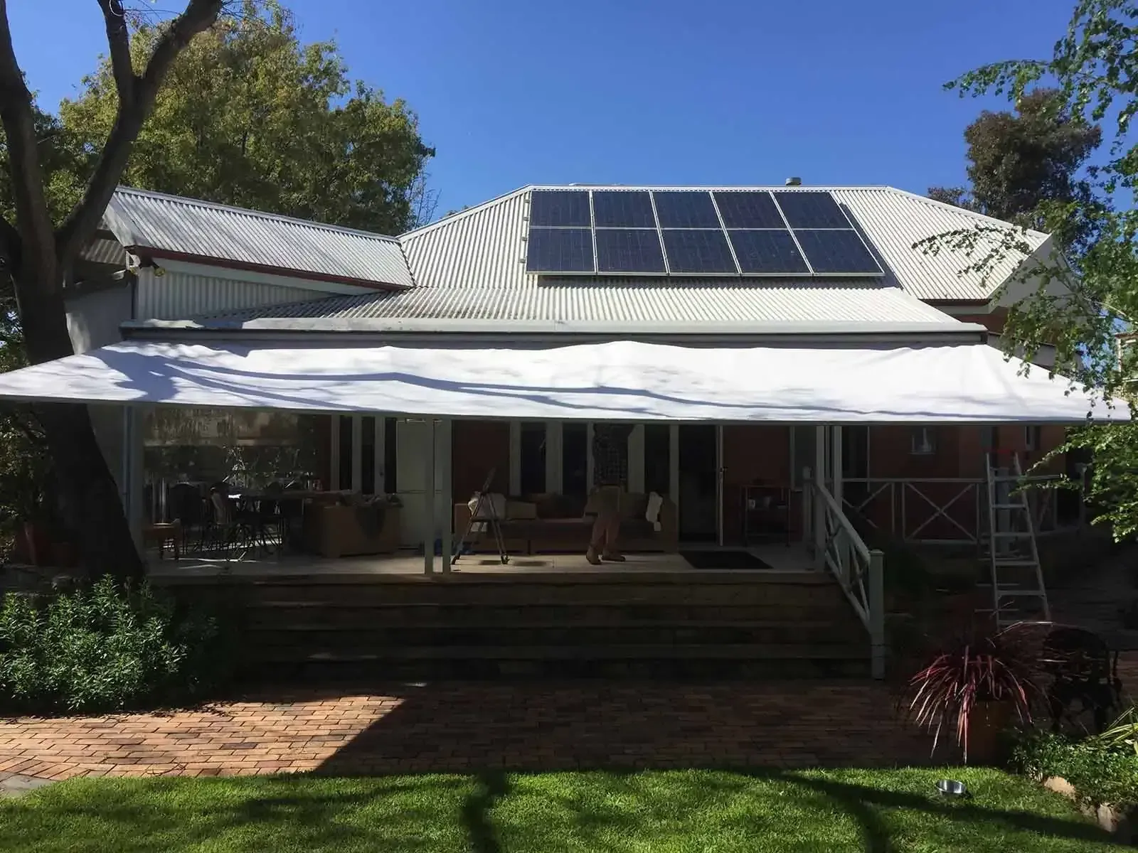 A House With A White Awning And Solar Panels On The Roof — Spring Crest Blinds, Awnings & Security Doors in Golden Square, VIC