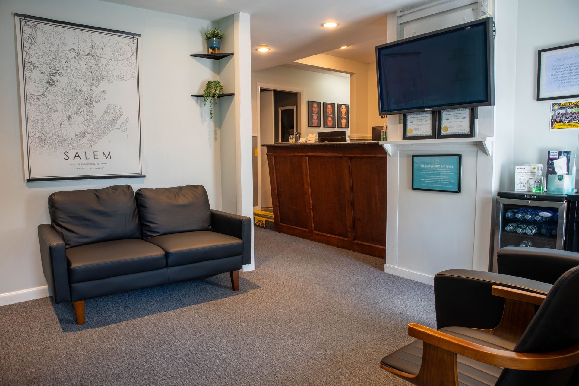Cozy lobby with gray sofa, wood reception desk, wall-mounted TV, and carpeted seating area