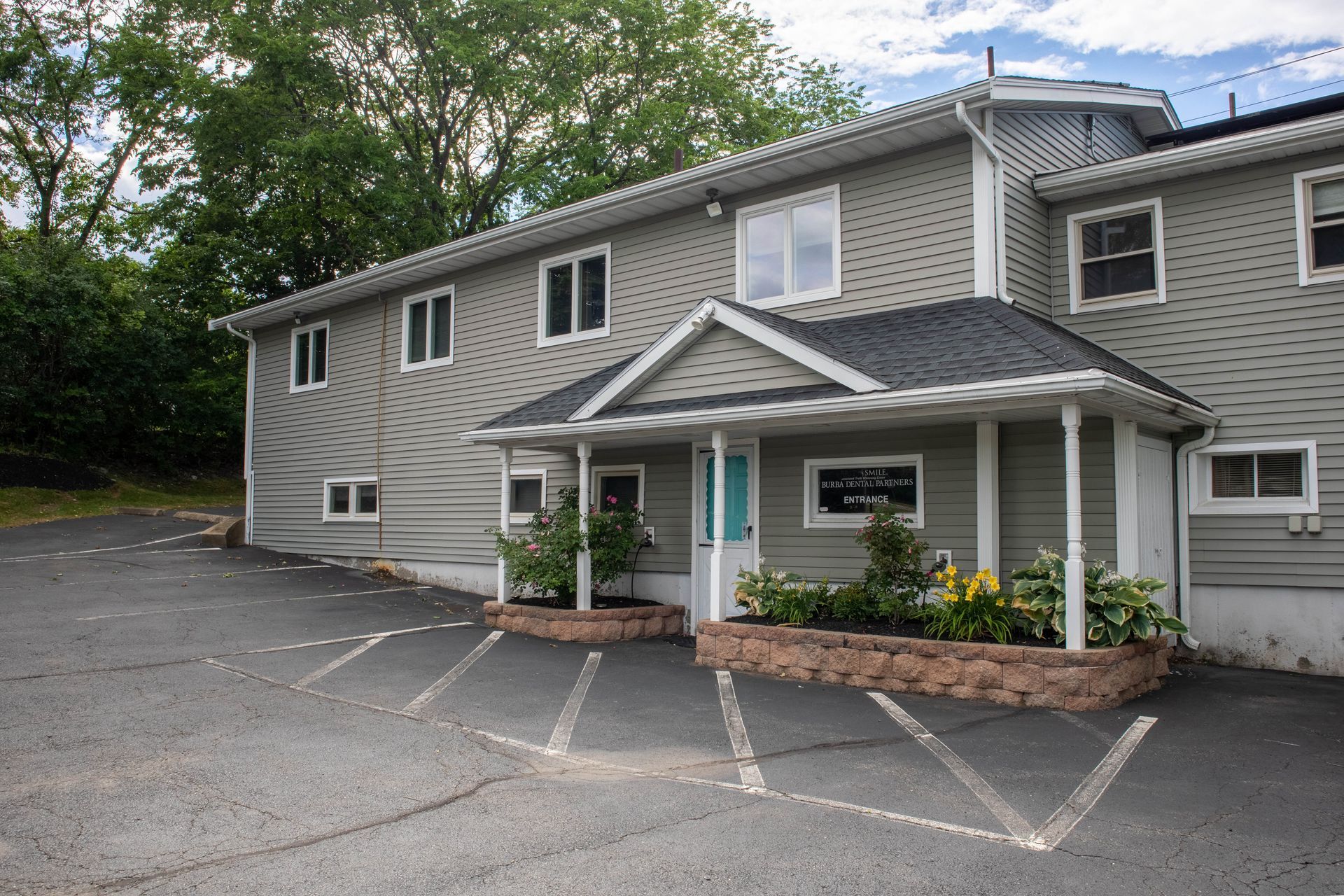 Gray two-story building with a small covered entrance and a paved parking lot