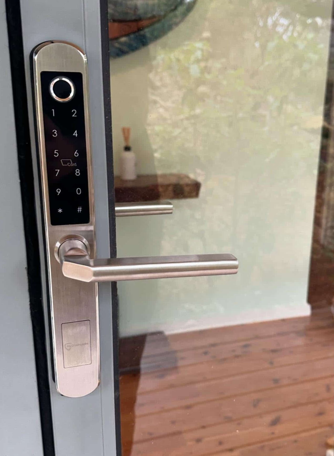 Silver Smart Lock With Keypad and Handle on a Glass Door — Great Ocean Locksmiths in Belmont, VIC
