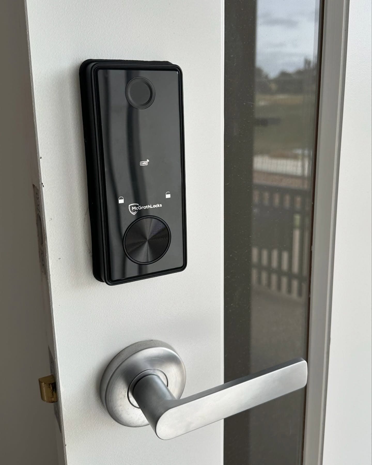Black Smart Lock on a White Door Next to a Silver Door Handle — Great Ocean Locksmiths in Torquay, VIC