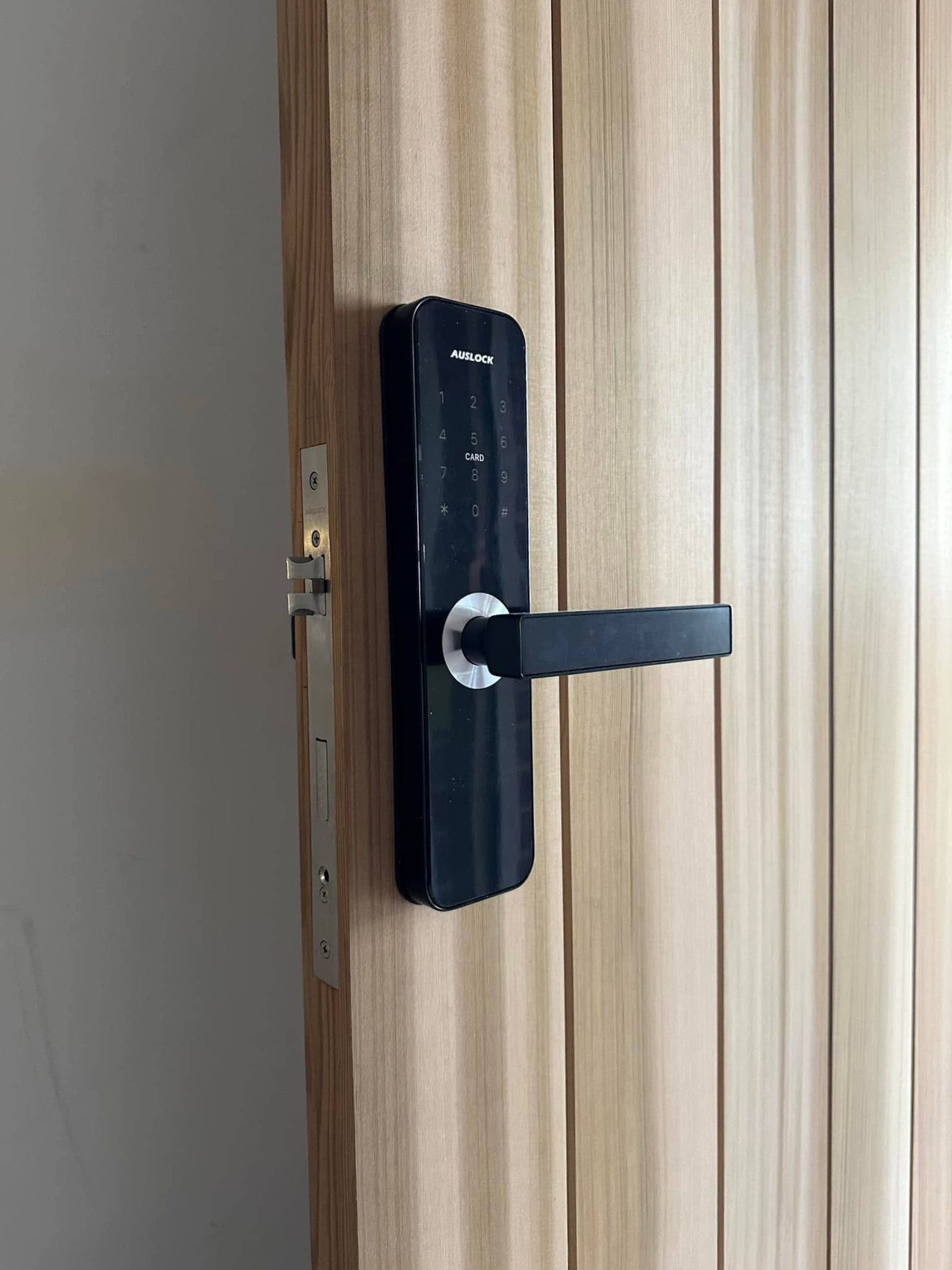Black door handle on a light-coloured wooden door — Great Ocean Locksmiths in Belmont, VIC