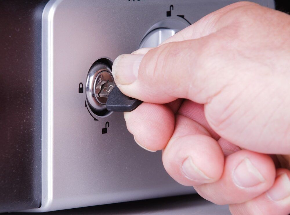 Hand Turning a Key in a Lock on a Silver Metal Surface, Unlocking a Mechanism — Great Ocean Locksmiths in Belmont, VIC