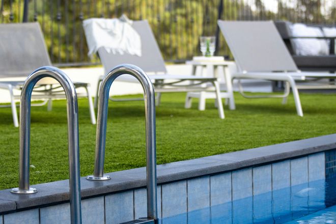 Poolside area showcasing artificial grass with lounge chairs in a comfortable outdoor area