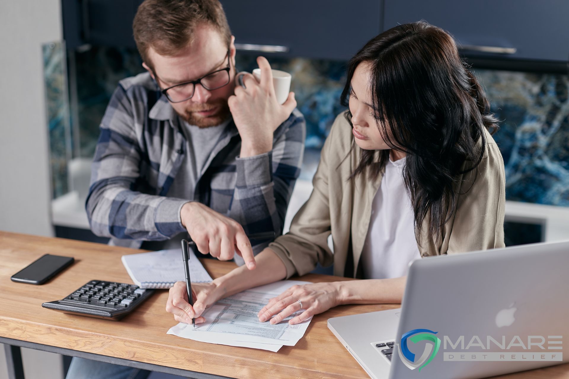 couple thinking if does a debt settlement hurt your credit sitting at a desk in front of a laptop