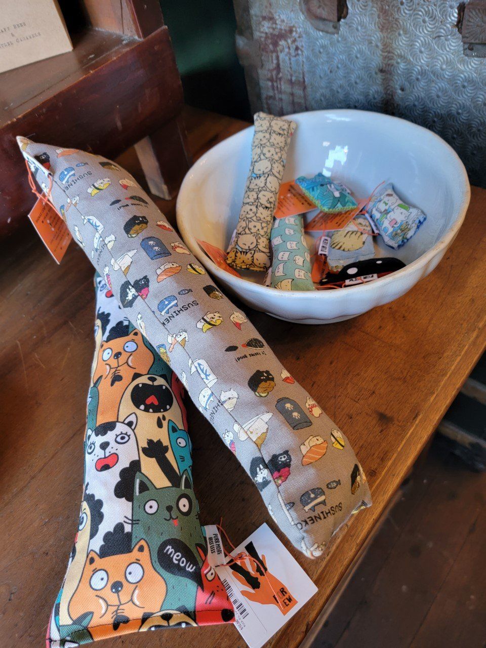 Catnip toys in a bowl and on a wooden surface, featuring cat and dog patterns.