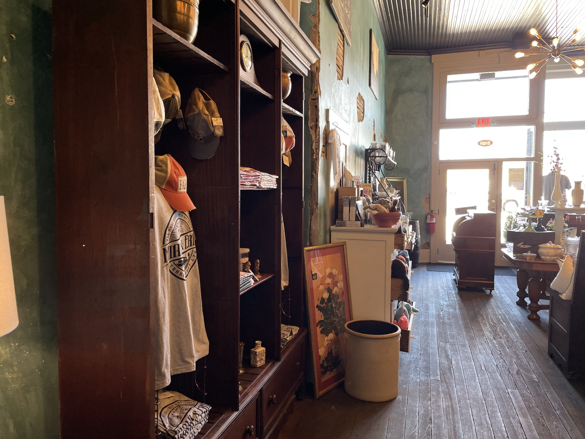 Inside a shop with wooden shelves displaying hats, t-shirts, and other merchandise. 