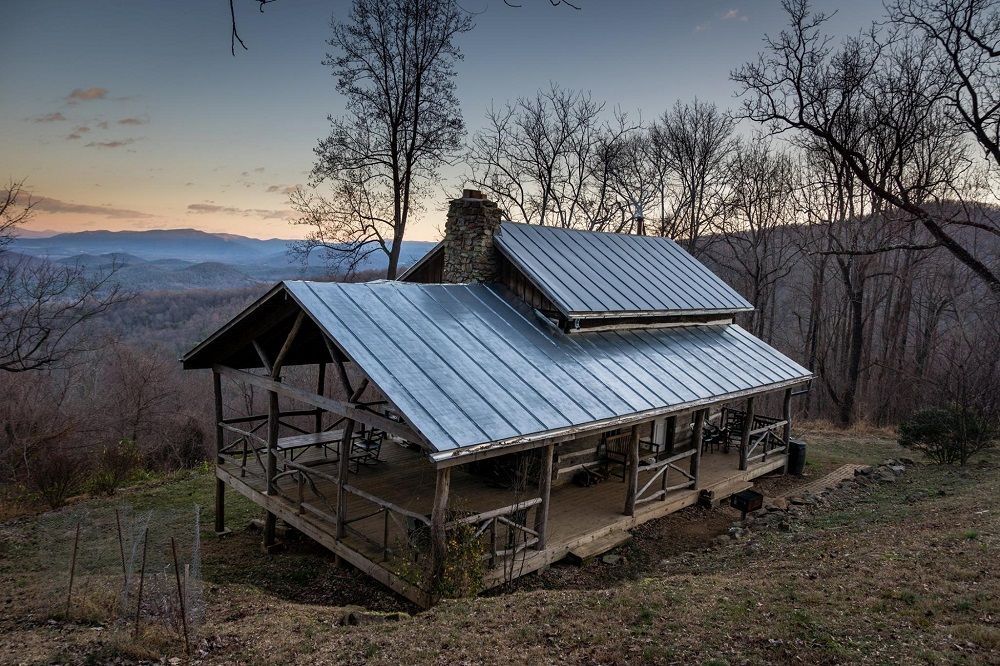 A small house with a metal roof is sitting on top of a hill.