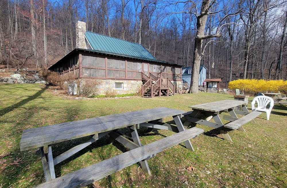 A picnic table is sitting in the grass in front of a house.