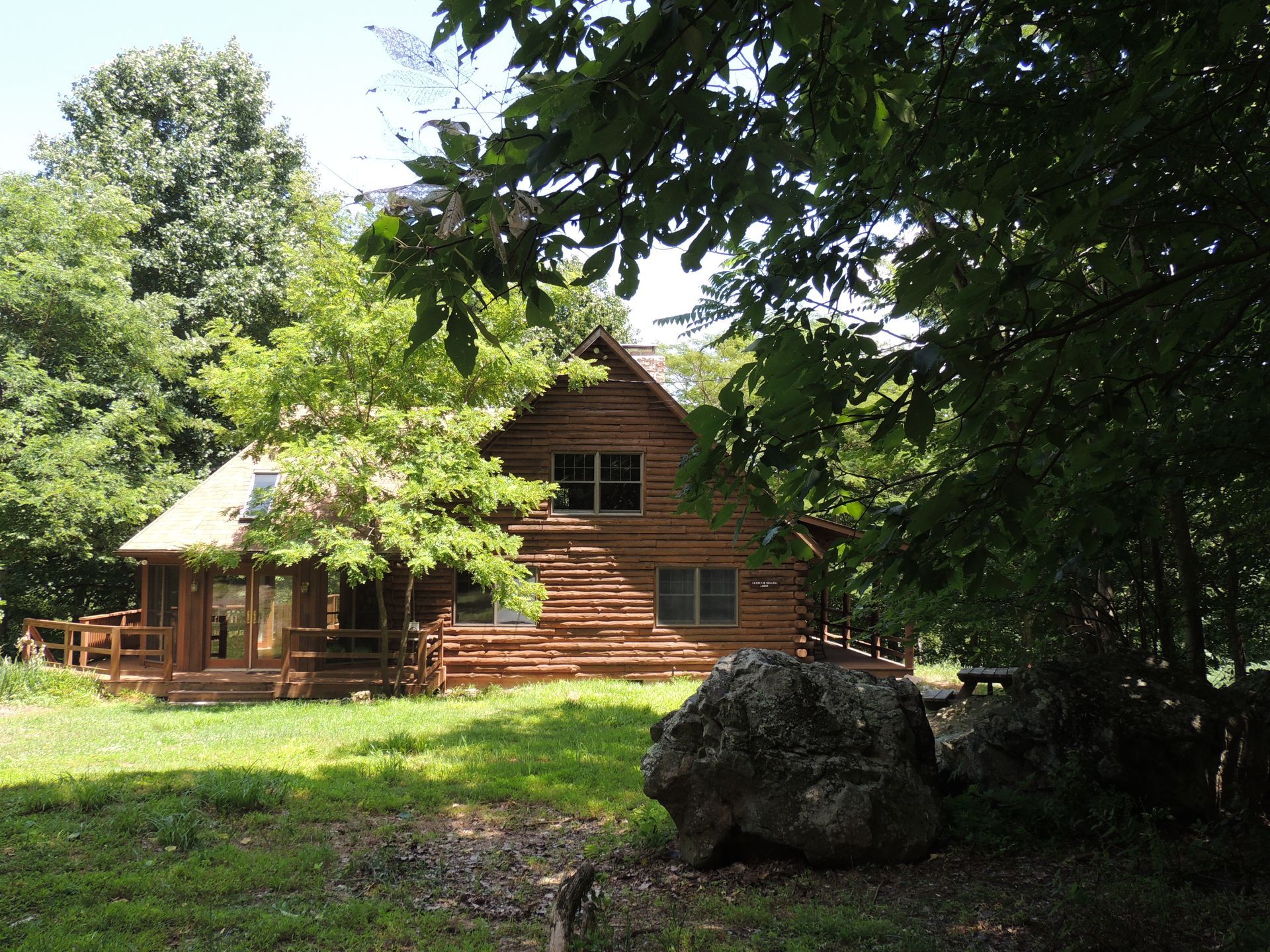 A log cabin sits in the middle of a lush green field