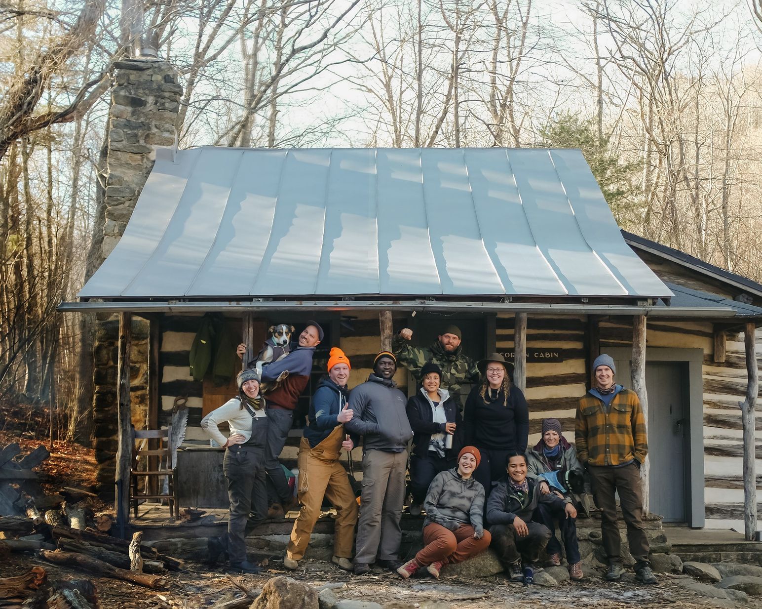 A group of people are posing for a picture in front of a log cabin.