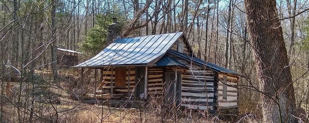 An old log cabin in the middle of a forest.