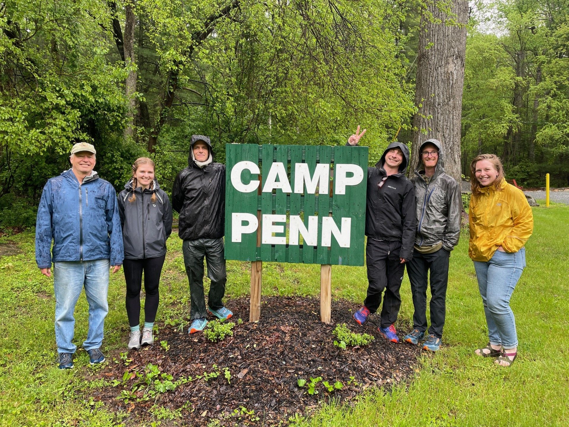 A group of people are standing in front of a camp penn sign.