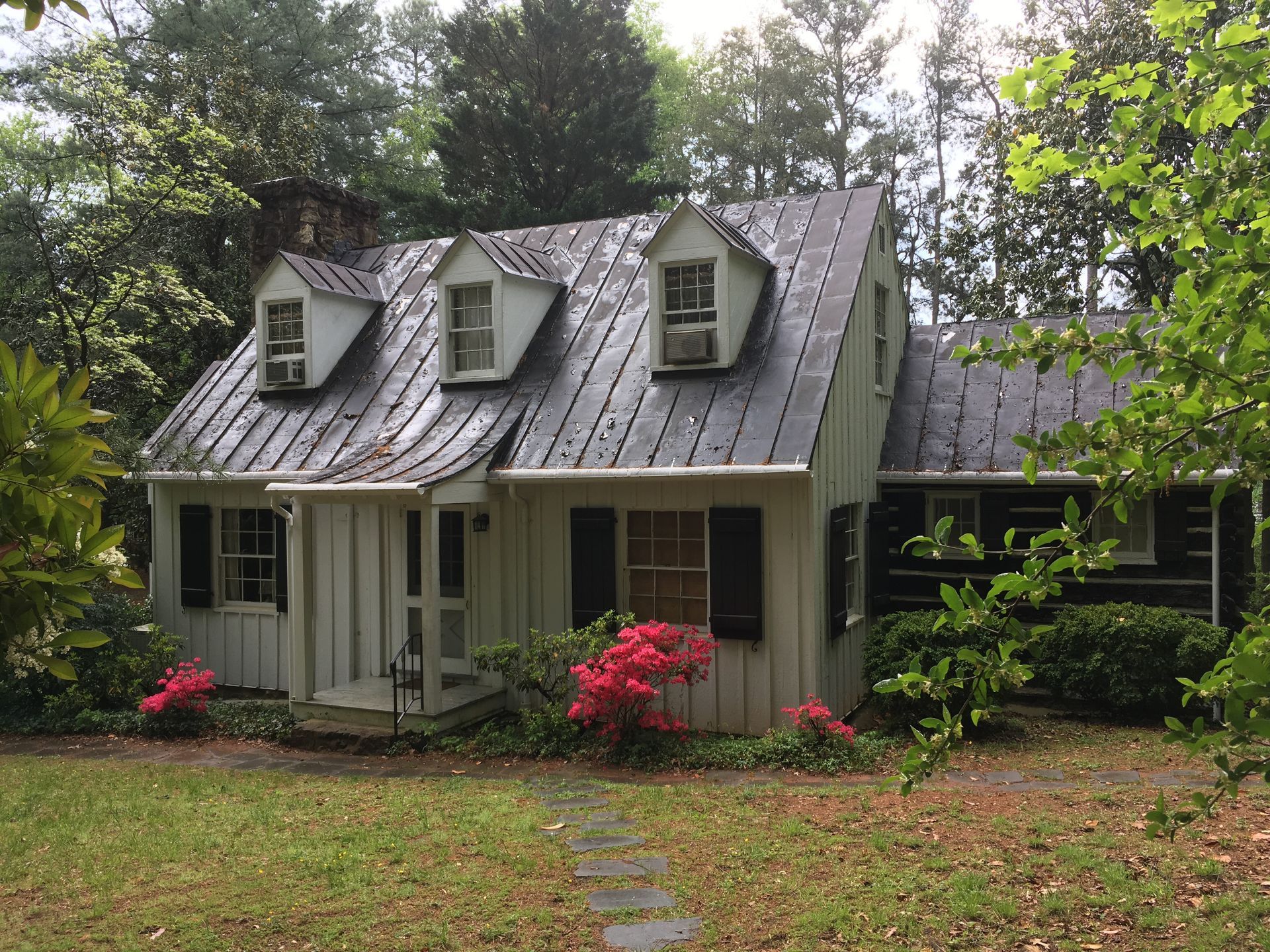 A white house with a metal roof and black shutters