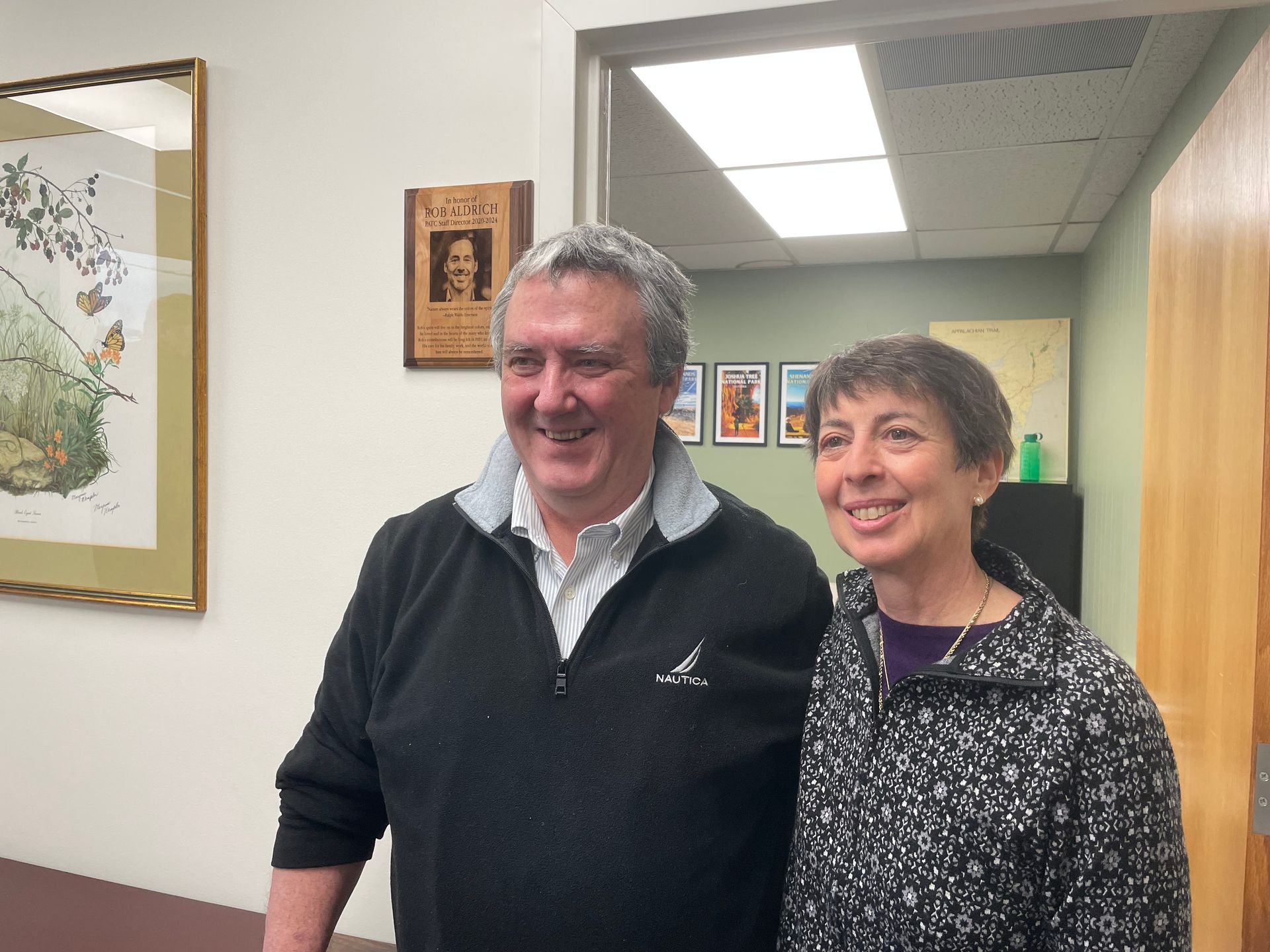 A man and a woman are posing for a picture in a hallway