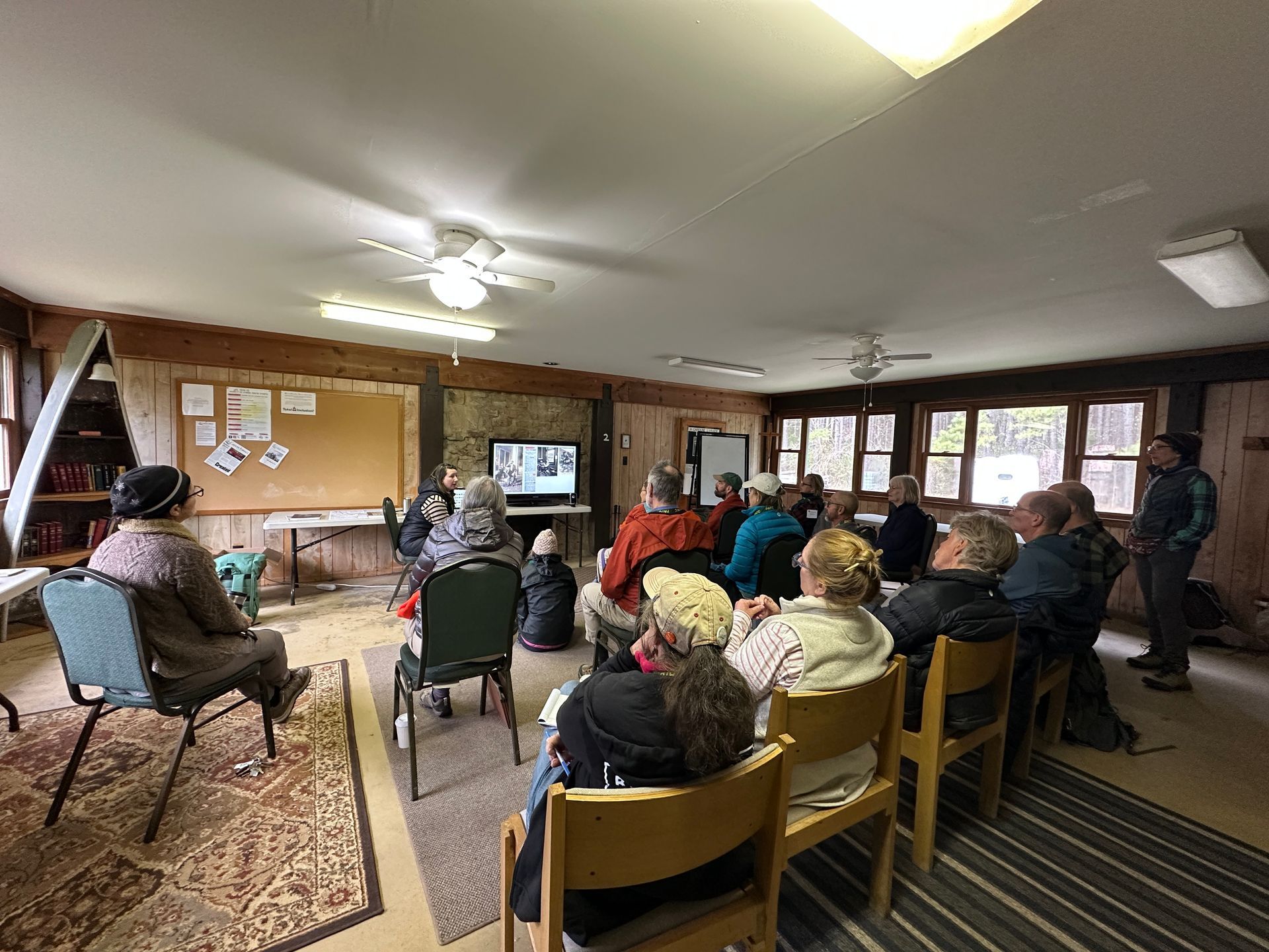 A group of people are sitting in chairs in a room watching a presentation.