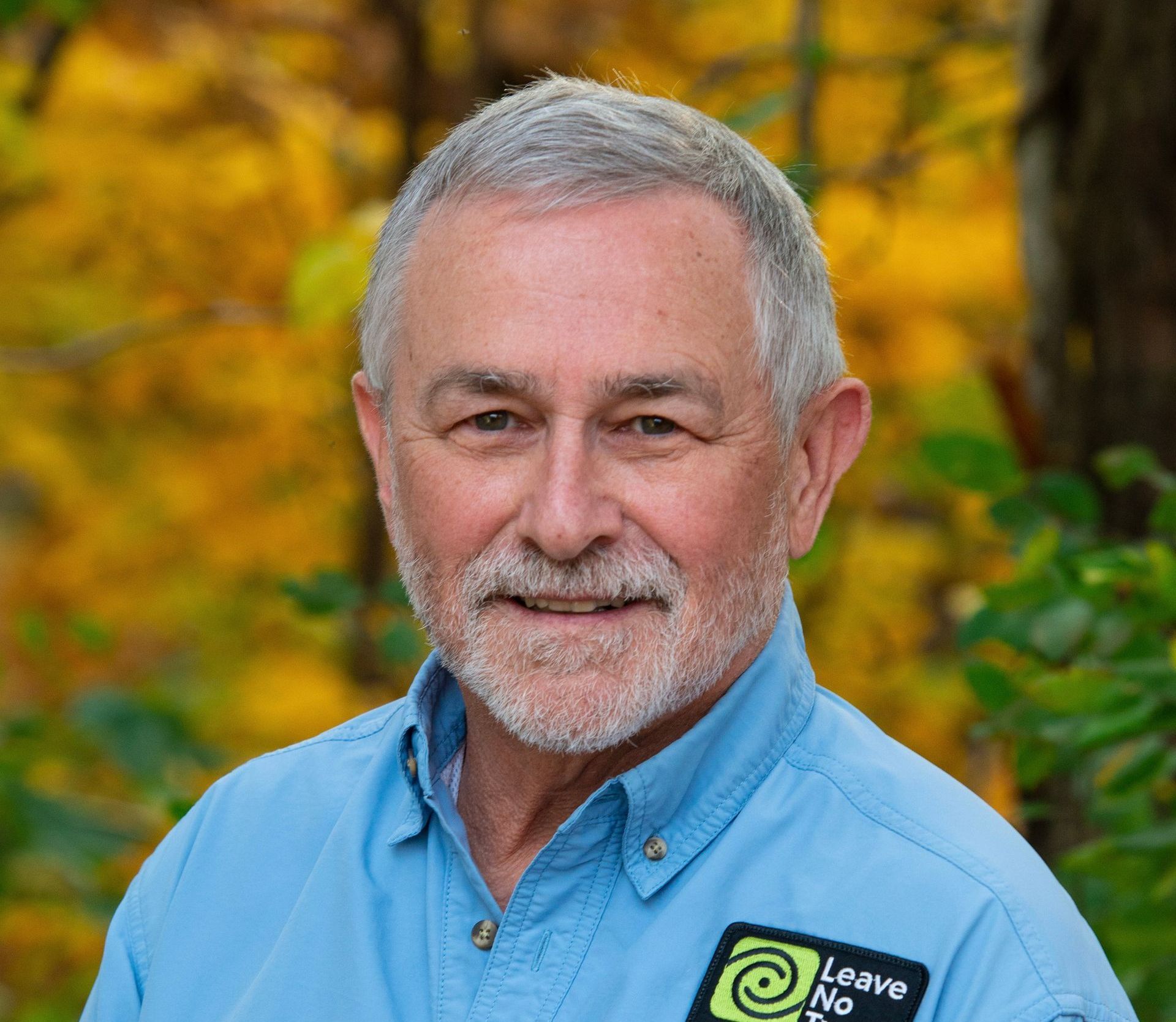 A man with a beard and a blue shirt is smiling for the camera.