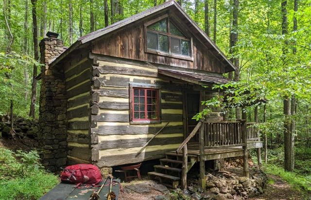 A small log cabin in the middle of a forest.