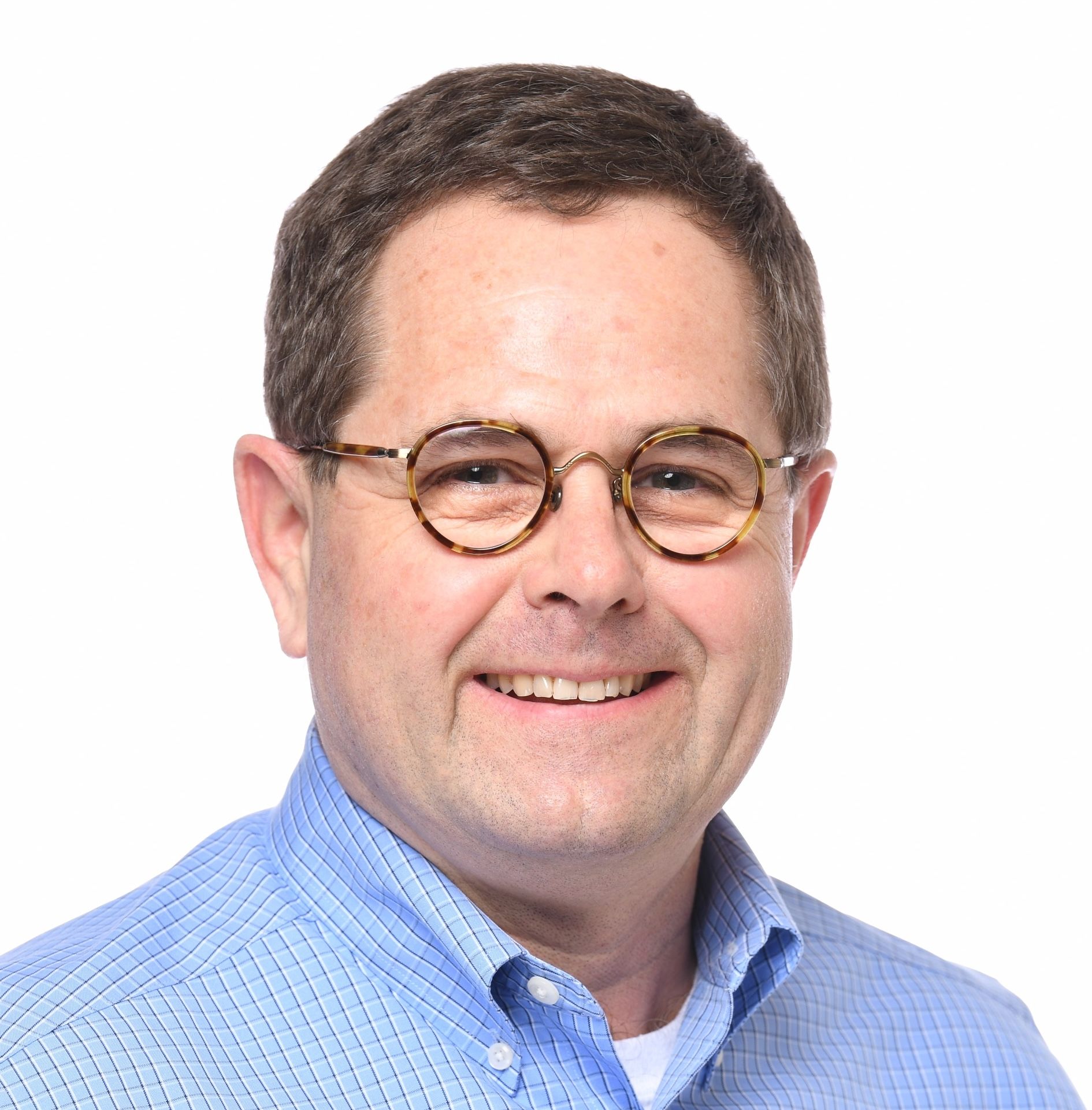 A man wearing glasses and a blue shirt smiles for the camera