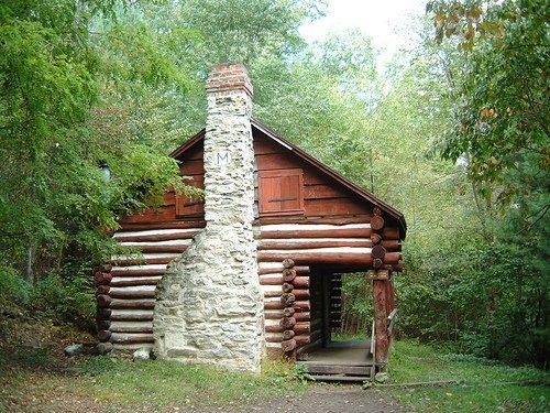 A log cabin with a stone chimney in the middle of a forest
